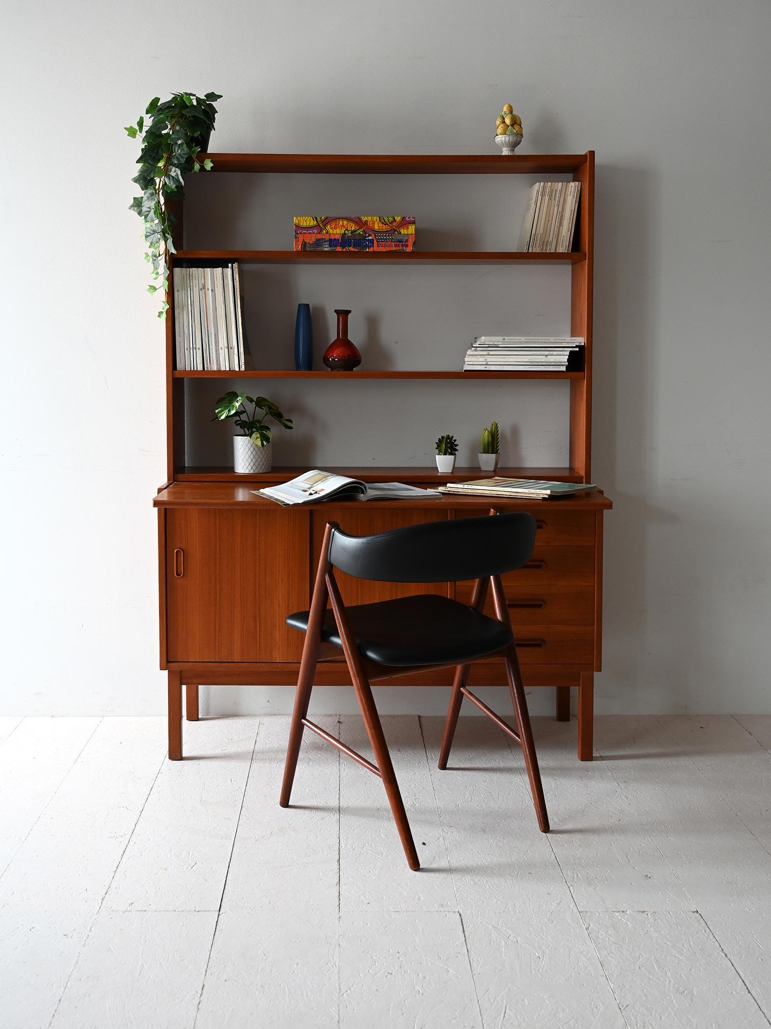 Vintage Scandinavian teak bookcase with built-in desk, shelves and sideboard with sliding doors and drawers.

Vintage Scandinavian teak bookcase, complete with a built-in desk, shelves and a base frame with a small sideboard. The sideboard has