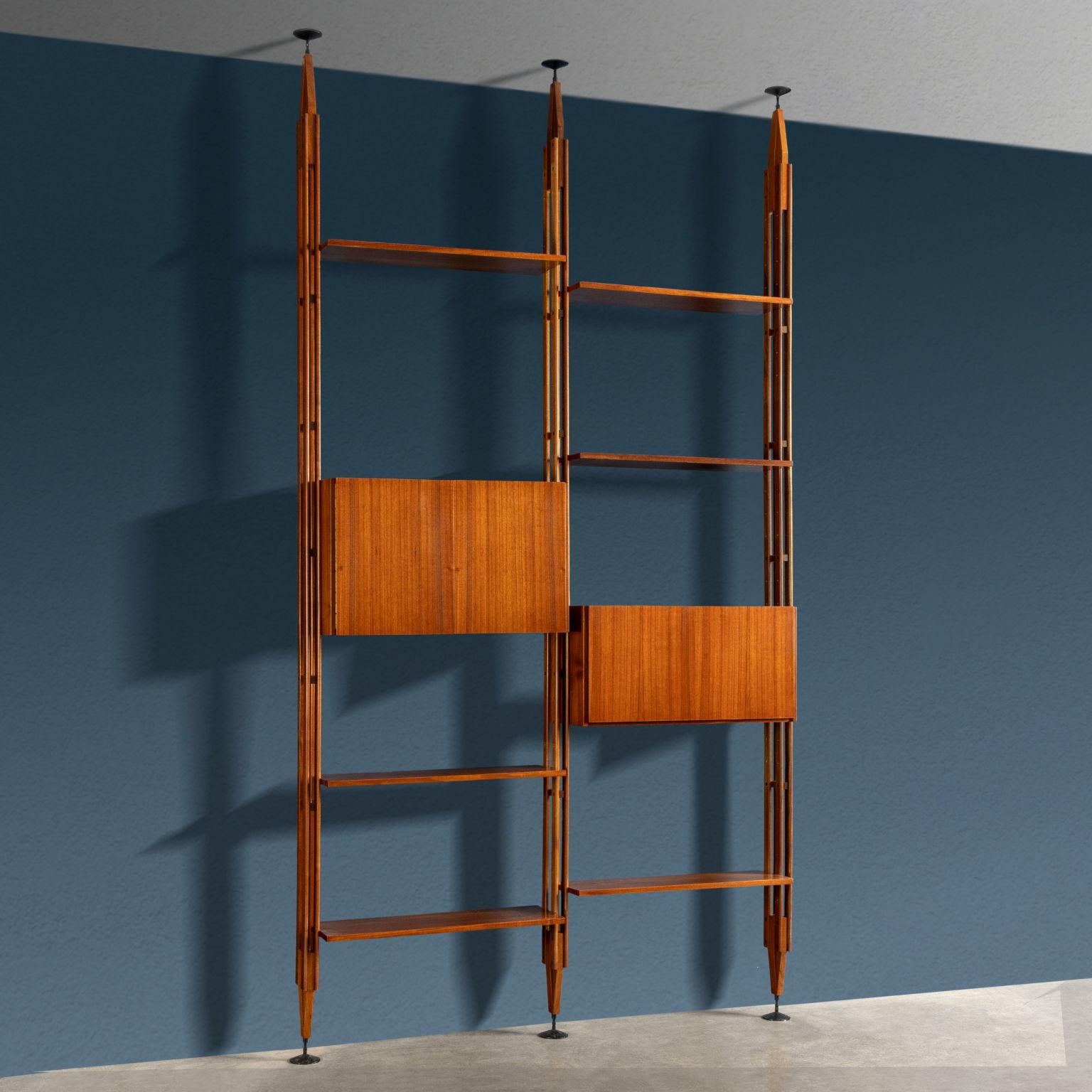 Iconic ceiling bookcase, also usable from the center, model 'LB7', designed by Franco Albini and produced by Poggi from the late 1950s.
The bookcase features two bays with solid teak wood uprights pressure-fixed between the ceiling and floor,