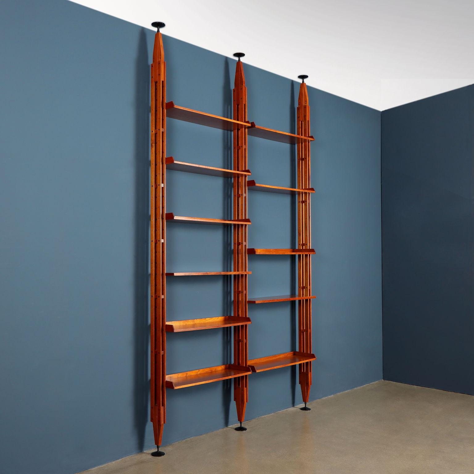 Iconic ceiling bookcase that can also be used as a centerpiece designed by Franco Albini and produced by Poggi starting in the late 1950s.
The bookcase - model 'LB7' - has two bays with solid teak wood uprights press-fitted between ceiling and