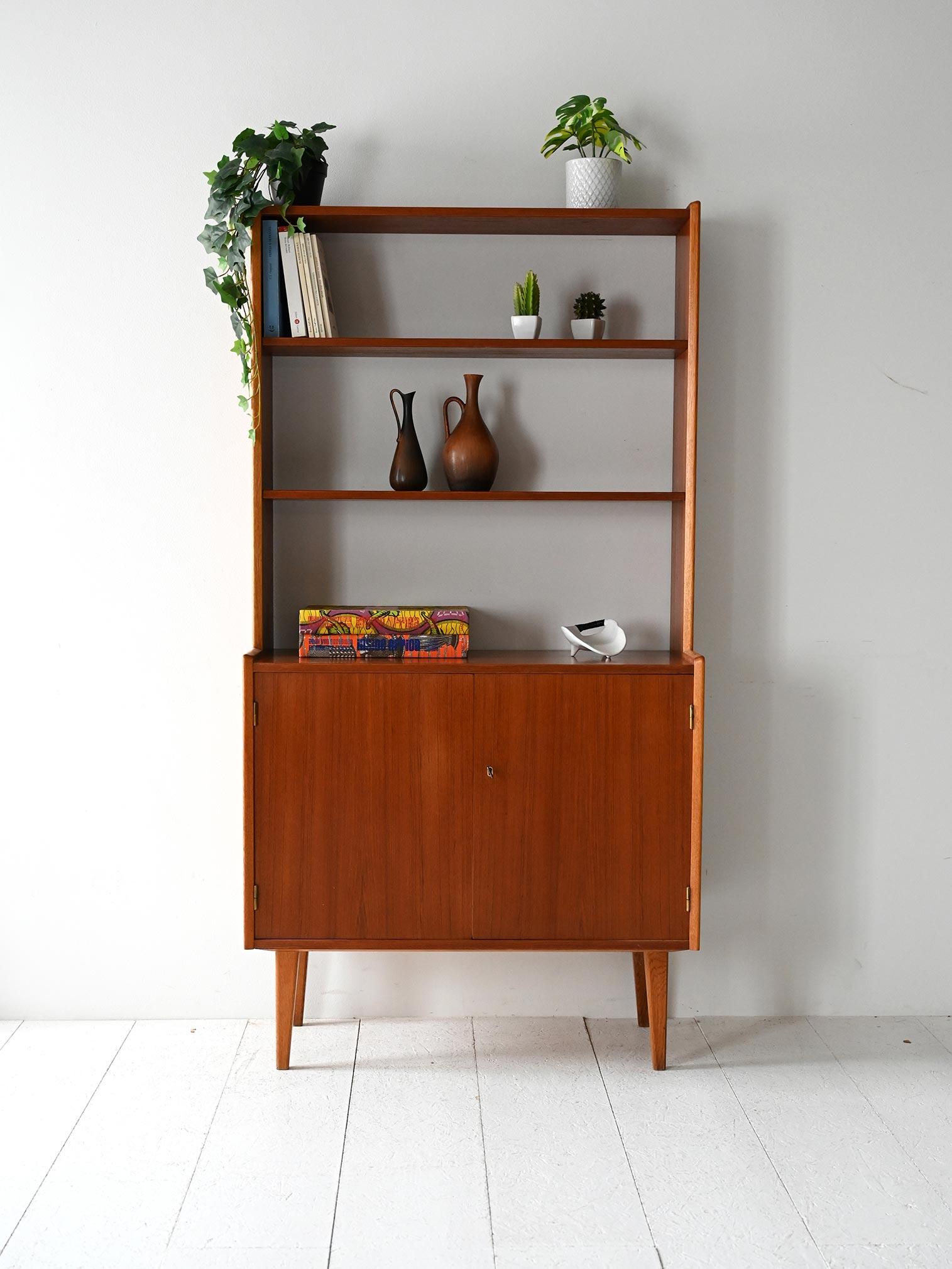 Libreria vintage in legno con base a due ante battenti, ripiano interno e parte superiore con mensole a giorno.

Libreria scandinava originale degli anni ’60 con struttura in legno e linee slanciate. La parte inferiore è dotata di due ante a