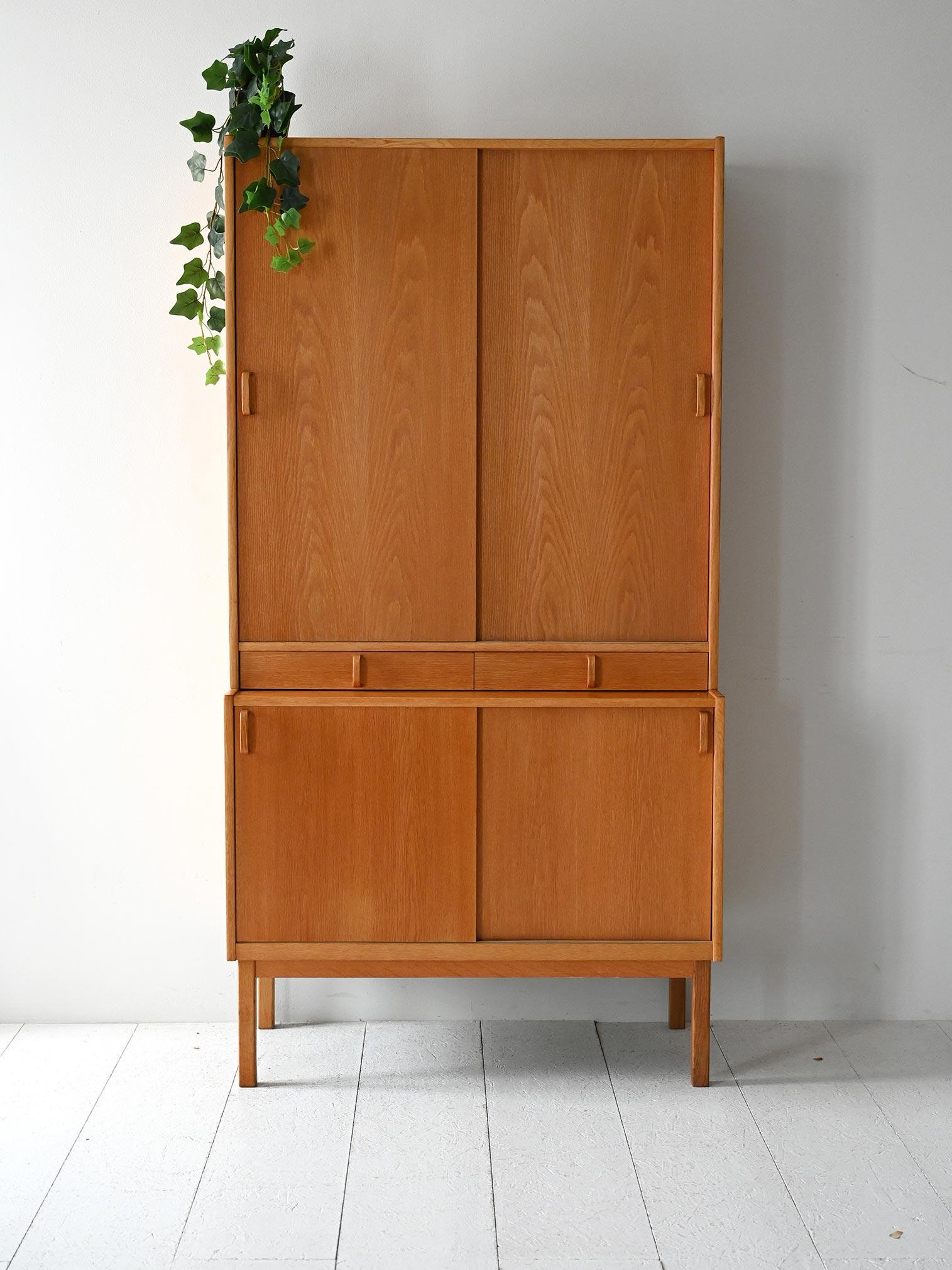 Libreria vintage a due corpi in rovere con ante scorrevoli, ripiani verde oliva e tre cassetti centrali integrati.

Libreria a due elementi firmata Bodafors e disegnata da Bertil Fridhagen, realizzata in Svezia negli anni ’60. La struttura in rovere