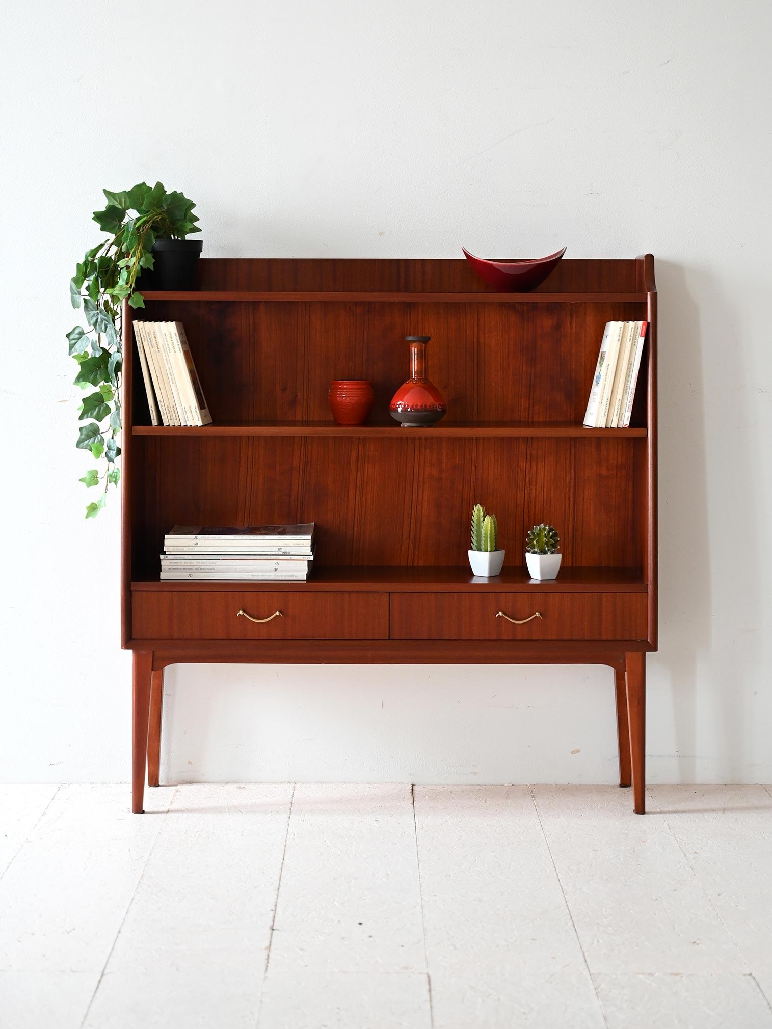 Vintage Scandinavian bookcase with sloping lines, slender mahogany frame, two lower drawers and open shelves in full mid-century style.

Scandinavian mahogany bookcase with an understated design and light proportions. The sloping lines of the sides
