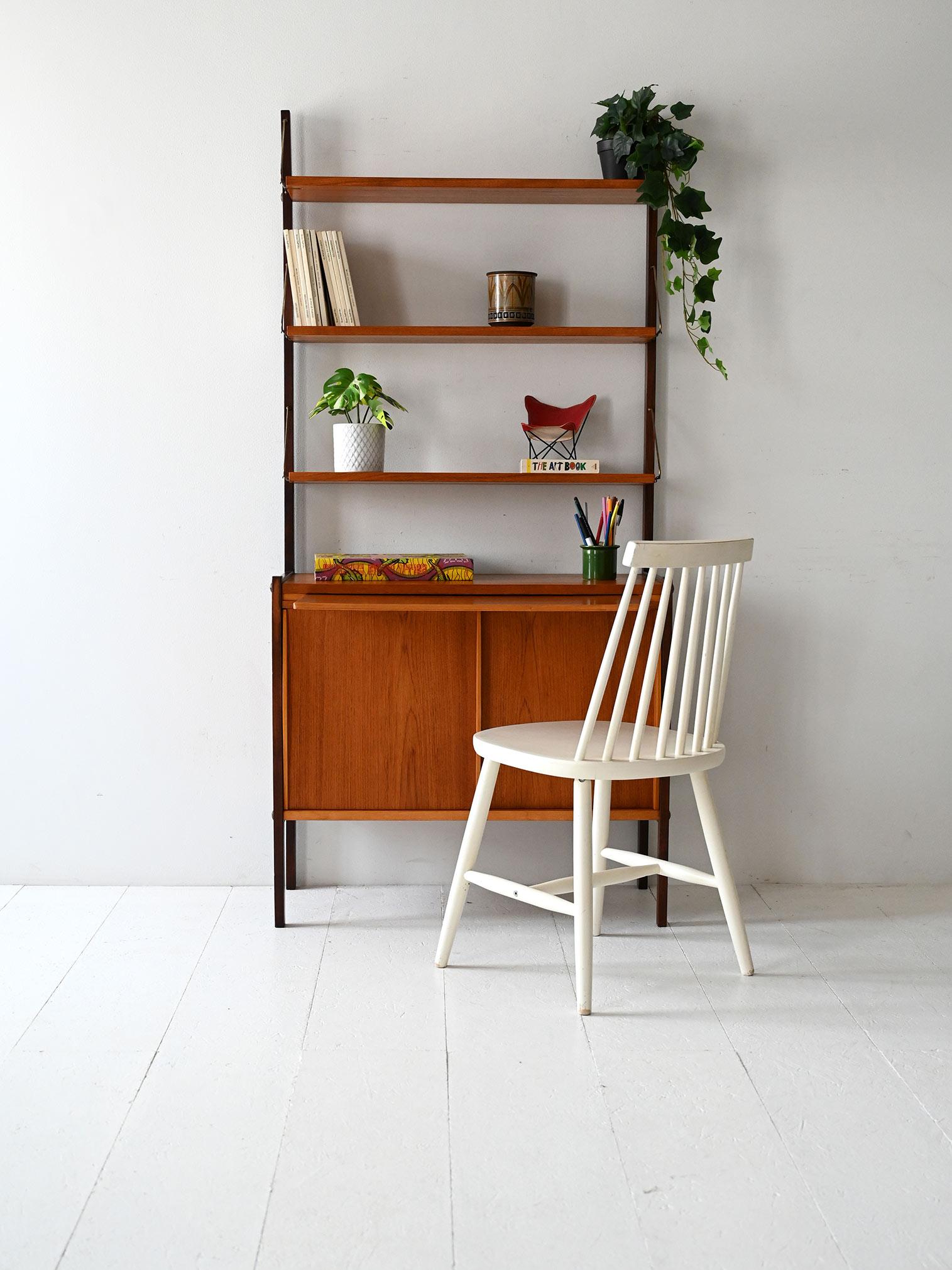 1960s bookcase with black painted wood uprights, exposed shelves, sliding doors, and pull-out desk.

Scandinavian bookcase from the late 1960s made of teak and painted wood. The structure consists of black uprights with exposed shelves supported by