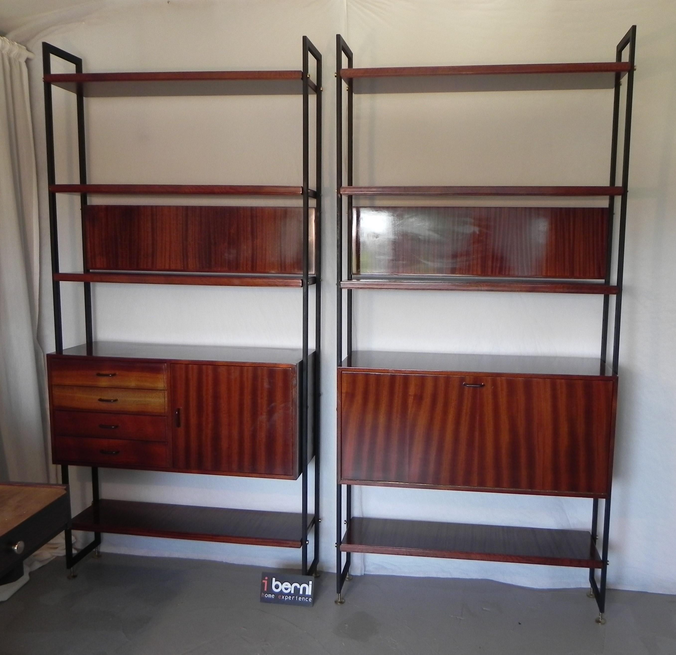 Libreria in stile danese, anni '60. Montanti in metallo, struttura ed ante in legno. Composta da due elementi accostabili: un elemento con ribalta bar e un elemento con cassetti ed antina. Ripiani e contenitori collocabili a piacere. Piedini in
