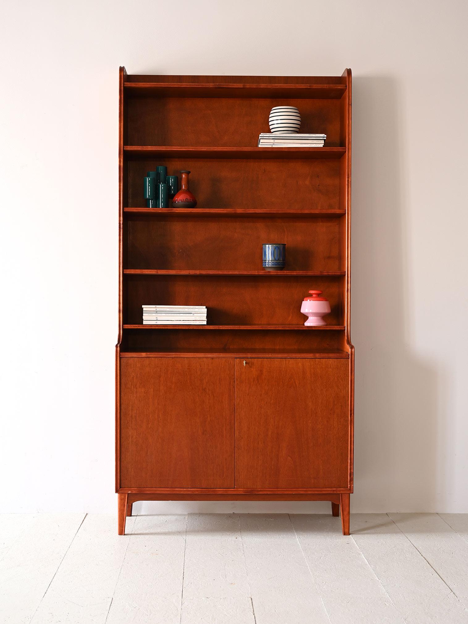 The shelves of this Swedish bookcase, help keep books and decorative items in order, while the doors below hide generous compartments for storing the less aesthetic elements of daily life. The balance between the warm vibrancy of the wood and the