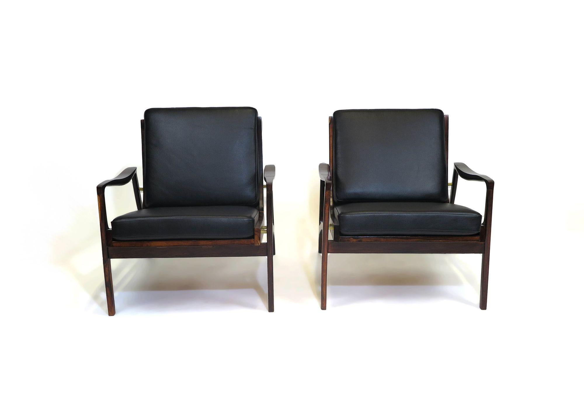 Liceu de Artes e Officios lounge chairs handcrafted from solid Jacaranda in a sculptural form with sloping arms and tapered edges. Newly upholstered in a full-aniline black leather. 
Measurements 
W 29.5'' x D 26'' x H 34.5''
Seat Height 16.5''.