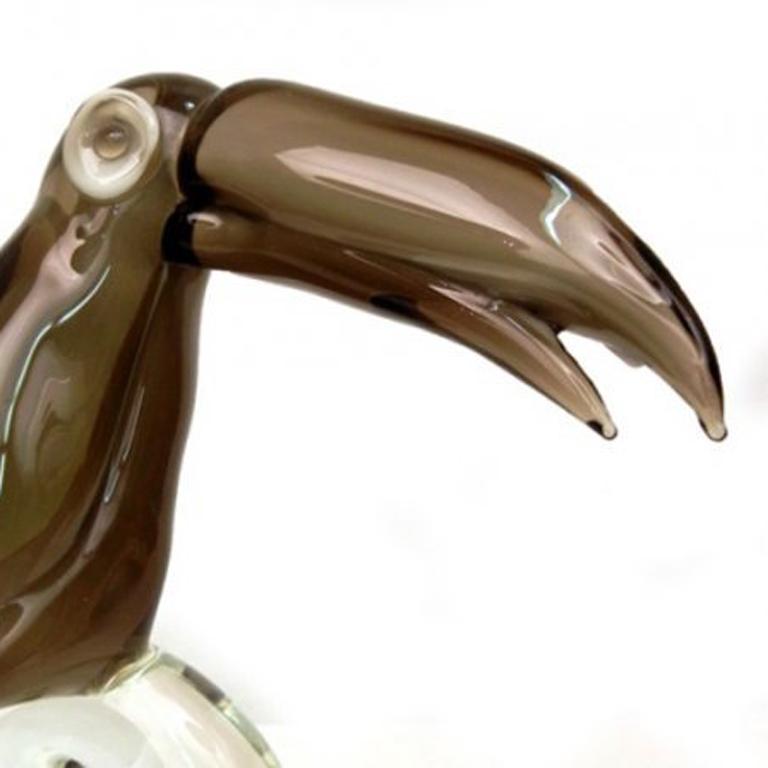 Uccello tucano su un ramo, realizzato da un maestro contemporaneo, in vetro di Murano fumé e trasparente soffiato a mano. La base è firmata a mano con la firma 
