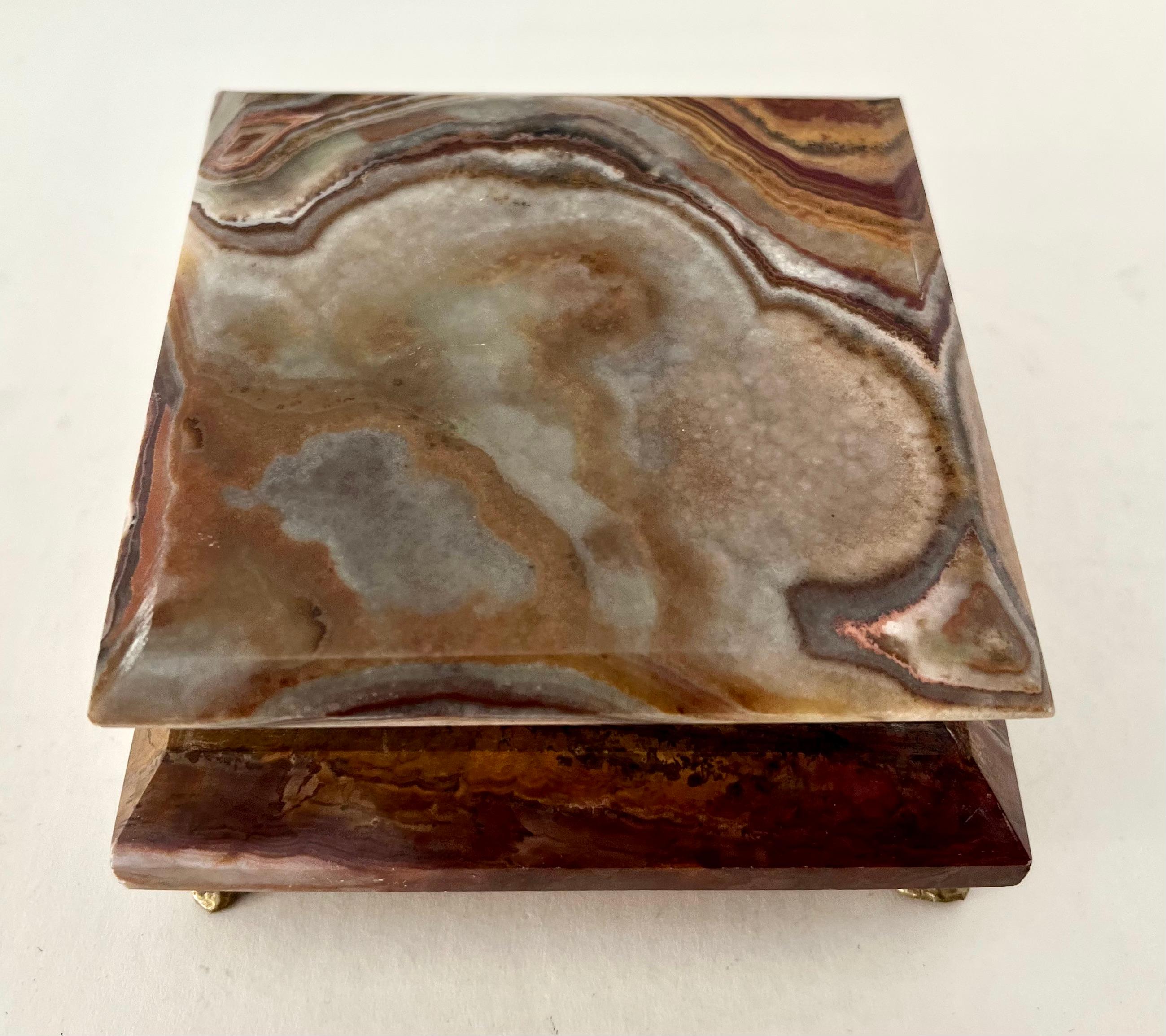 A wonderful Alabaster box, with a closure trimmed in brass and lined in red velvet. The brass paw feet give the hinged box a nice place to rest. 

A compliment to any valet or dressing table, nightstand or cocktail table - to hold things from
