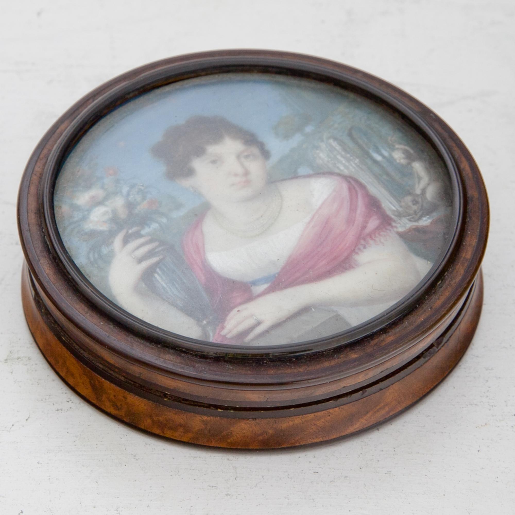 Round lidded box with portrait of a lady to the right, with a bouquet of flowers and a red scarf around the shoulders. Tortoiseshell box. Prov .: Collection of the Counts of Cao di San Marco.