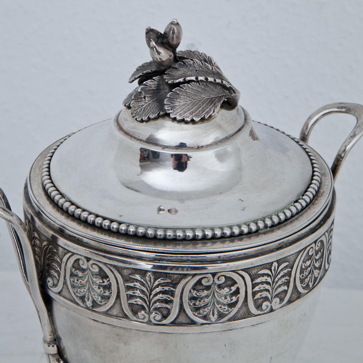 Silver lidded goblet (721g) on a round foot with bead molding and a conical wall, decorated with a palmette frieze and thin handles. The lid shows a knob in the shape of naturalistic rosehips. Marked at the bottom.