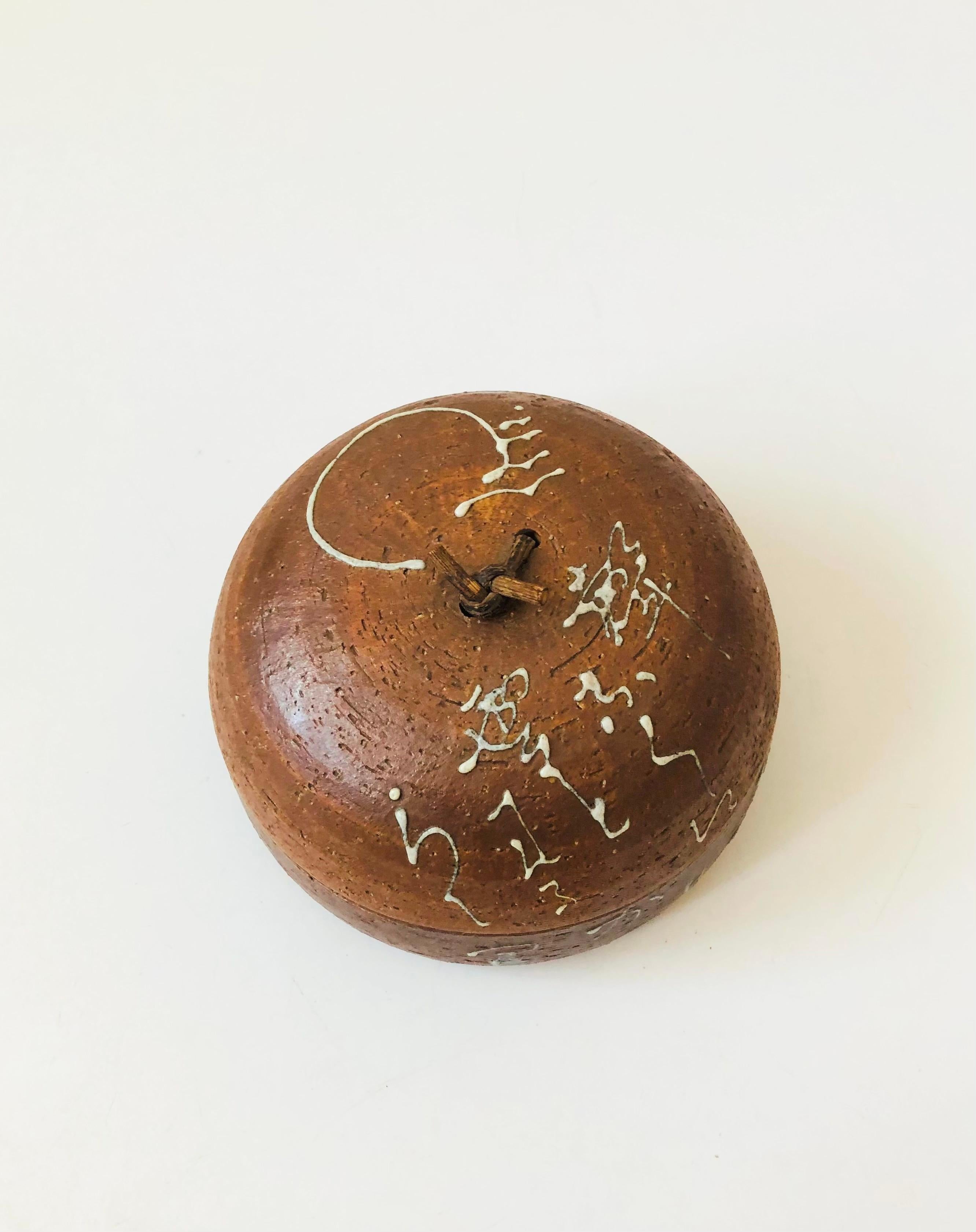 A beautiful vintage handmade pottery box. Natural clay color, decorated with a raised free form design in contrasting off-white glaze. Beautiful modern dome shape with a twisted twig as the handle. Glossy glaze to the interior. A truly special