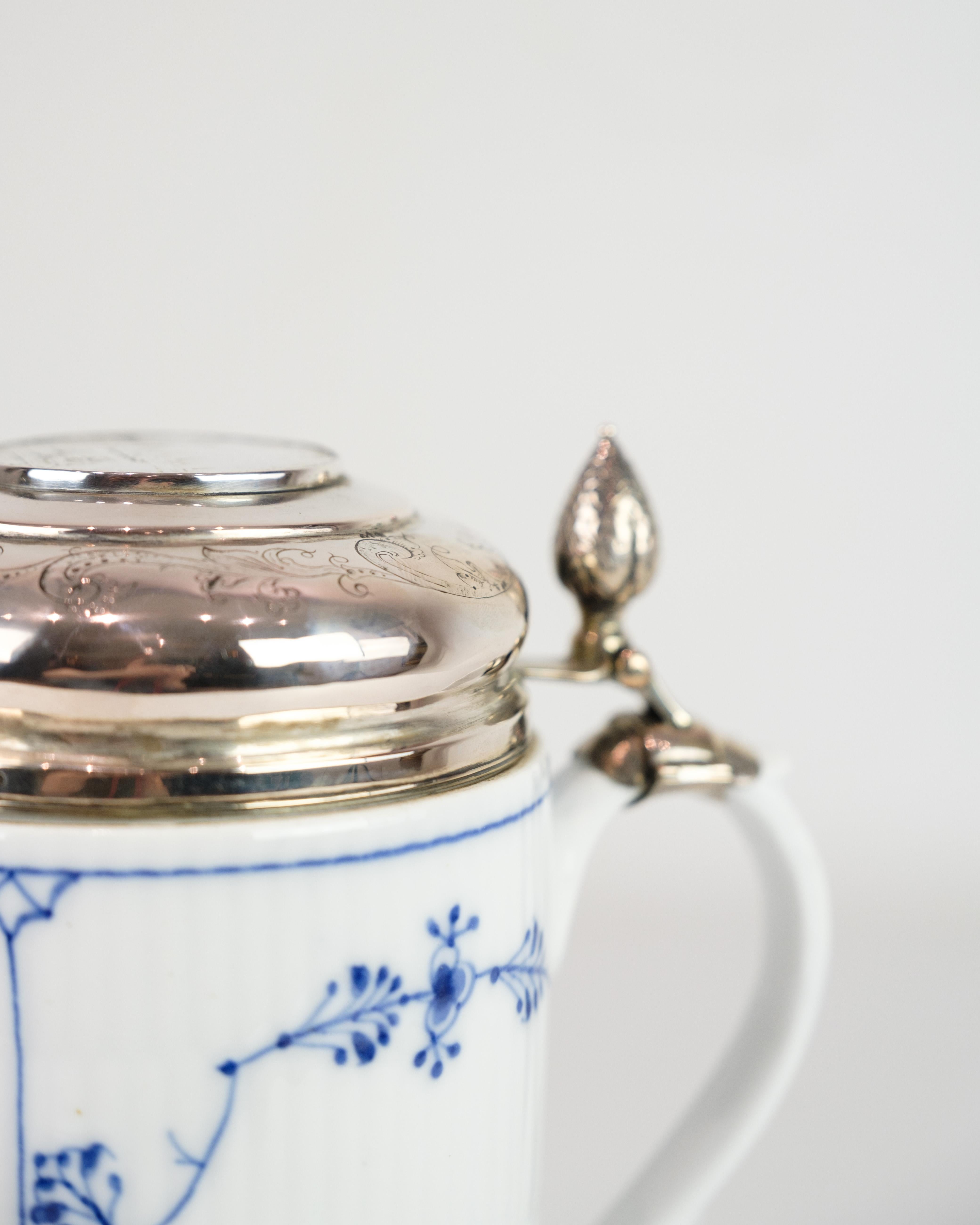 Lidded mug model 1/2023 from Royal Copenhagen, made of porcelain with classic blue fluting fluted decoration and baroque lid in silver. An elegant combination of Danish porcelain art and silversmithing.

Dimensions: H:17cm Dia:10.5cm