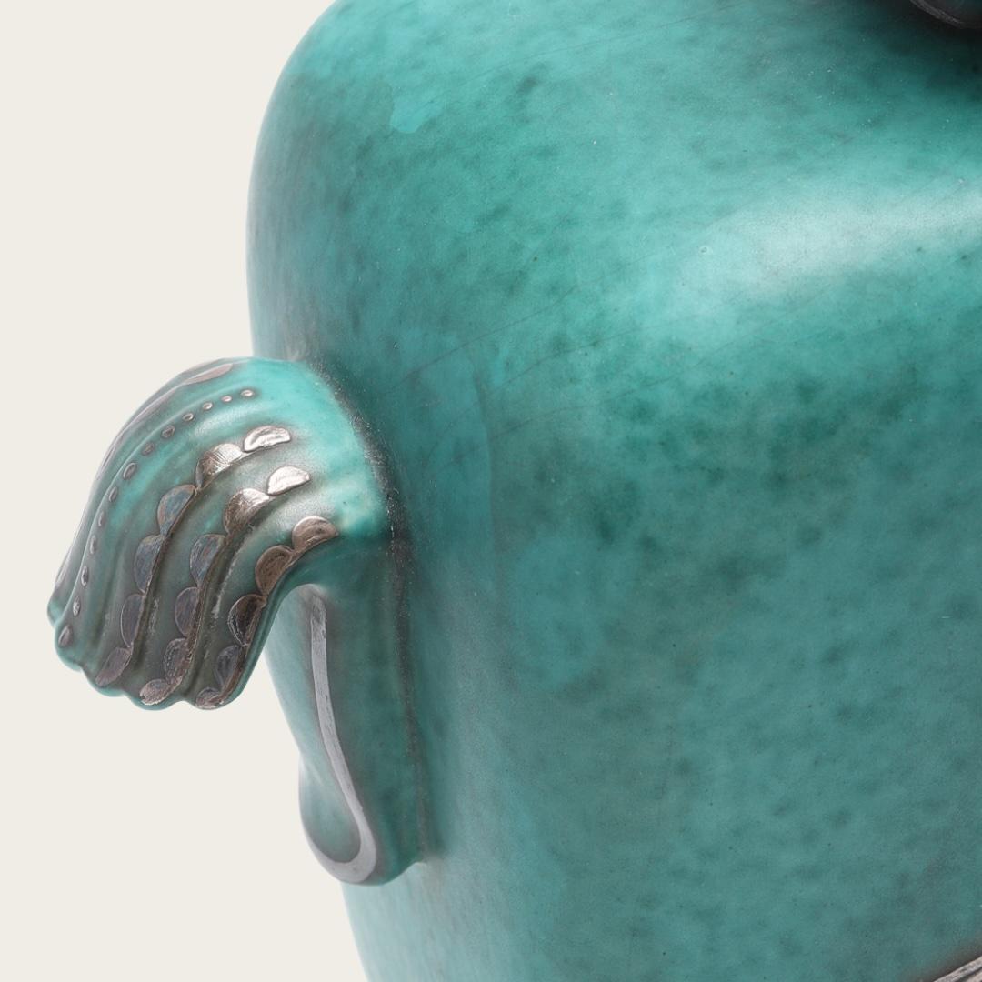 1934, Suède. Cette urne à couvercle en grès émaillé, modèle 1207, fait partie de la collection de grès Argenta de Wilhelm Kåge réalisée pour la manufacture de Gustavsberg. Il présente des décorations en feuilles d'argent représentant un oiseau avec