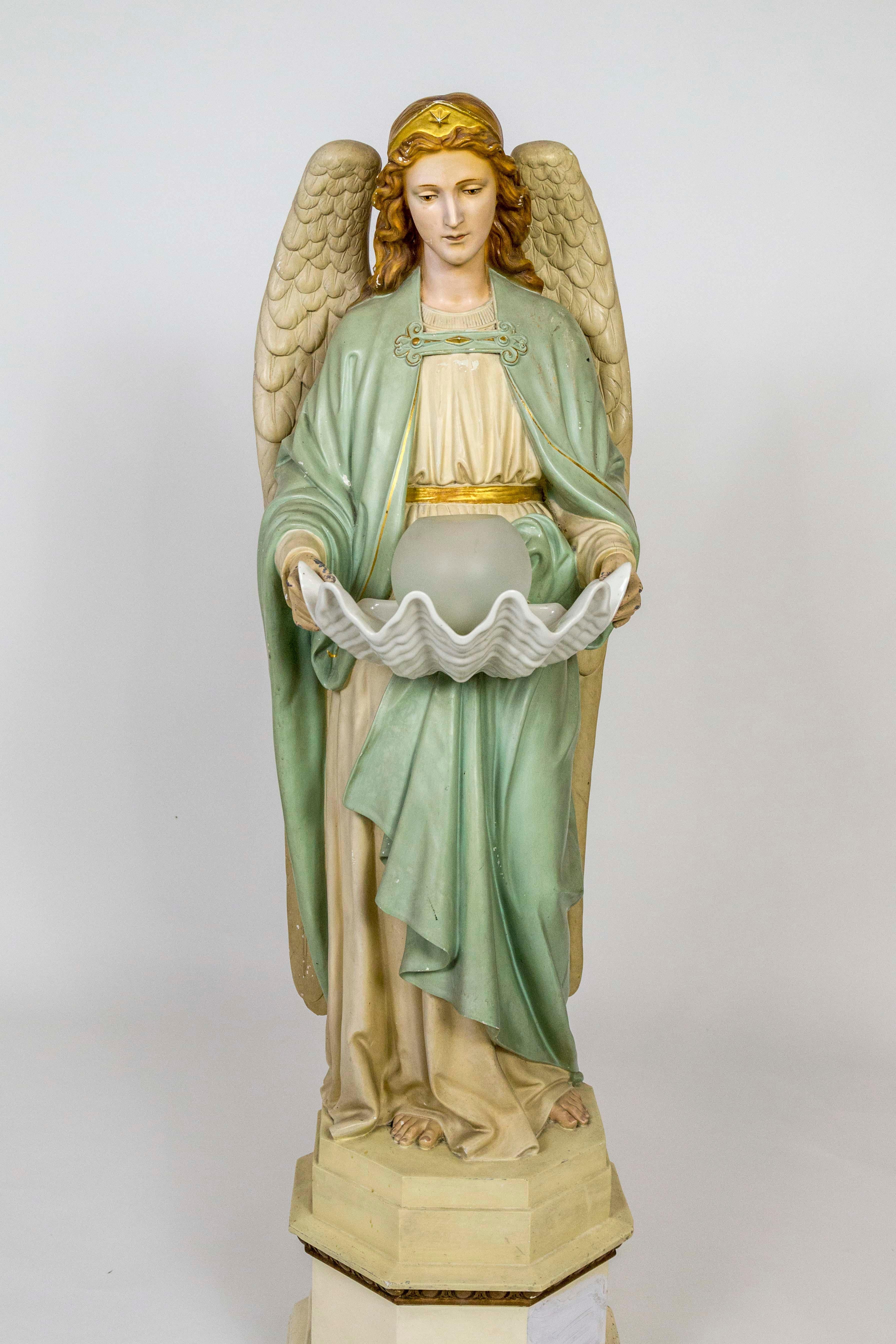 A life-sized, hand painted angel statue, holding a large, porcelain clam shell. In the shell is a removable, frosted glass ball shade with a light. Painted in a nice palette of color: dusty mint, gold, vanilla, and raw sienna. Made of plaster and