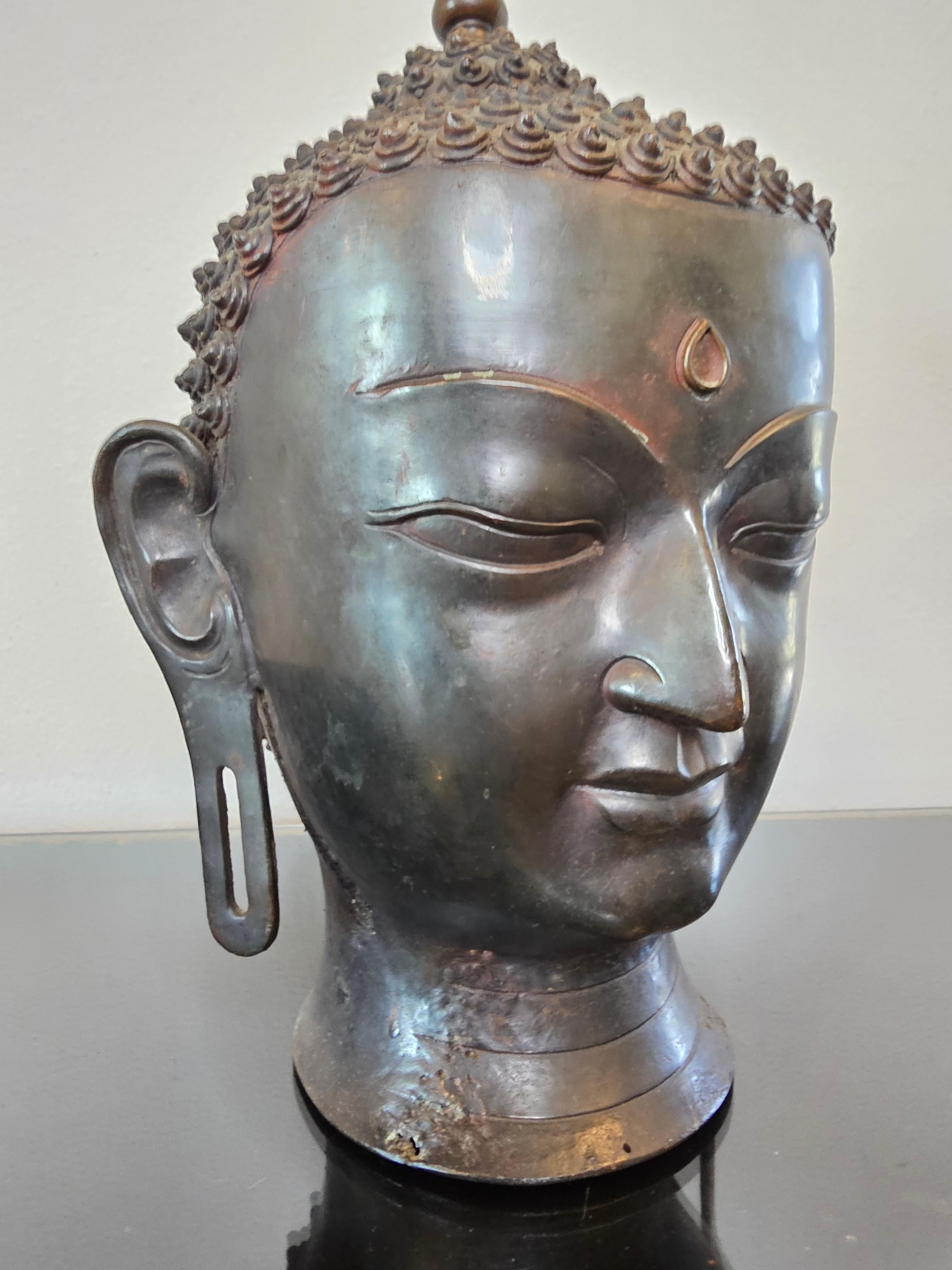 Impresionante cabeza de Buda del sur de Asia, de bronce patinado, antigua y de gran calidad.

Añade un toque de relajada calidez, elegante tranquilidad y armonía con esta llamativa y rara cabeza de Buda auténtica de tamaño natural. 

Es casi seguro
