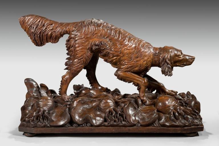 A life-size Black Forest carved lindenwood wood setter in a 'pointing' stance with a long plumed tail, his collar inscribed 'Nägler aus Gera' and the base 'St. Zechmeister.
