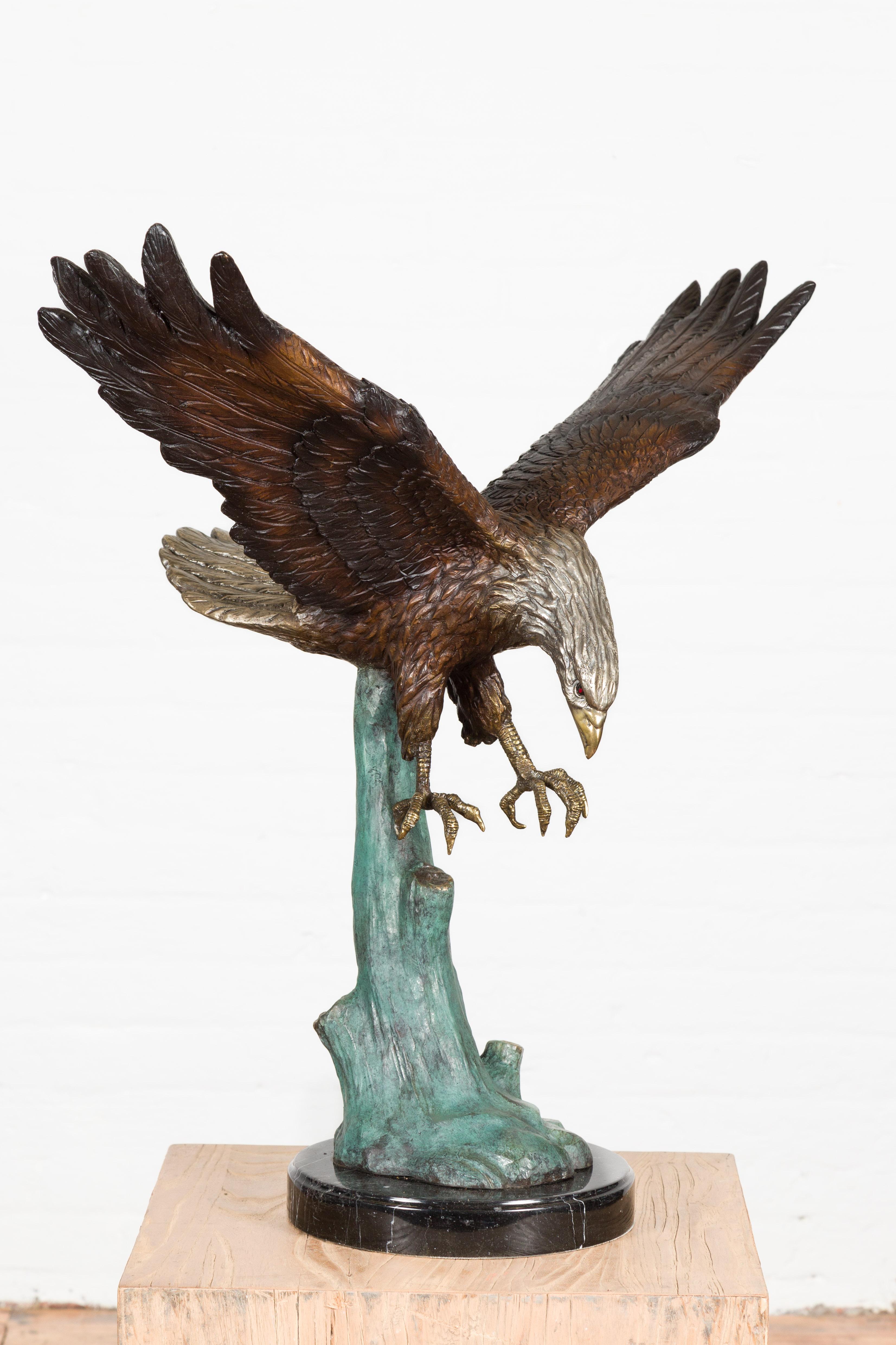 A lost wax cast bronze sculpture depicting a diving eagle, taking off from a tree on black marble base. This item is available now and this is also a current production. Created with the traditional technique of the lost-wax (à la cire perdue) which