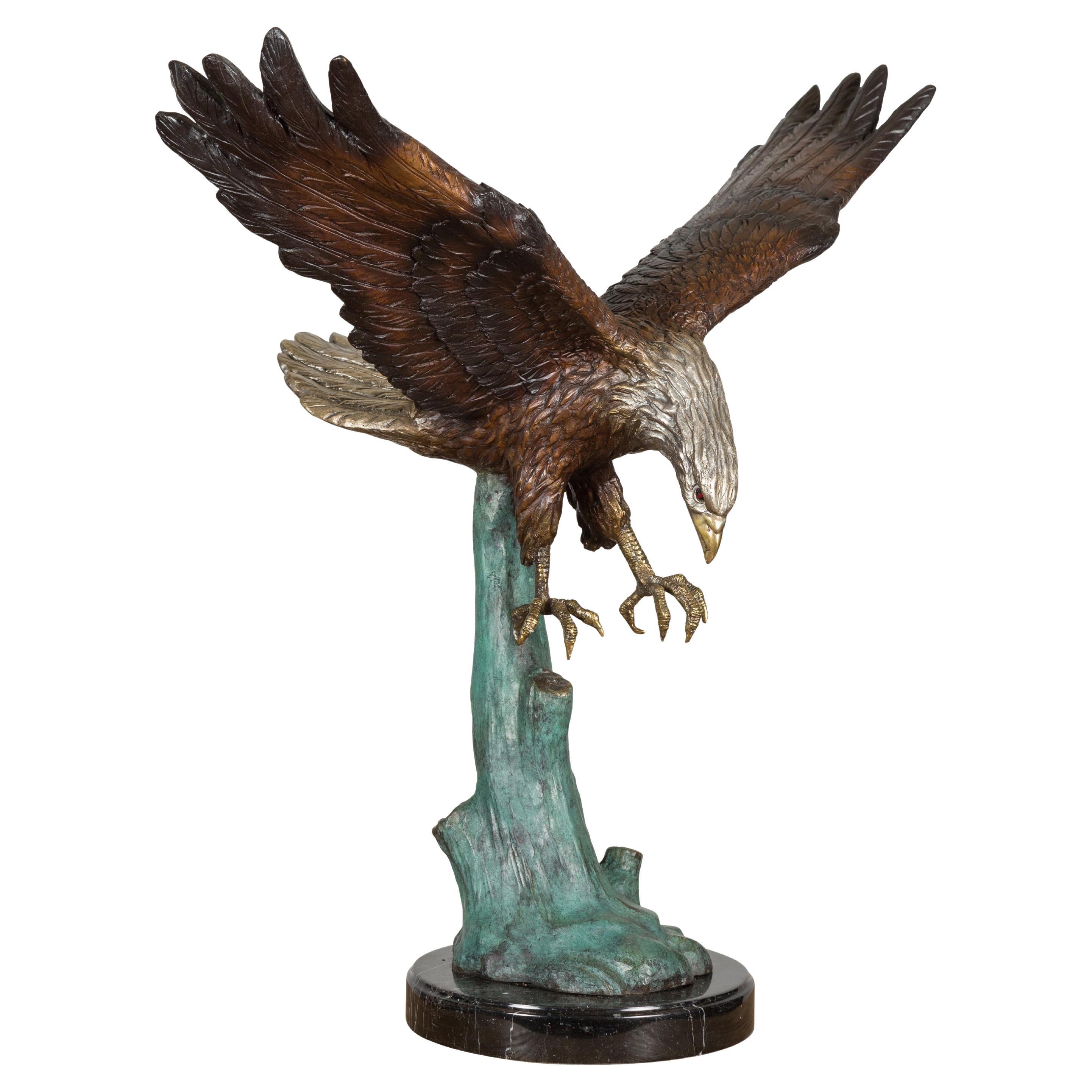 Sculpture en bronze grandeur nature d'un aigle en train de manger sur socle en marbre noir