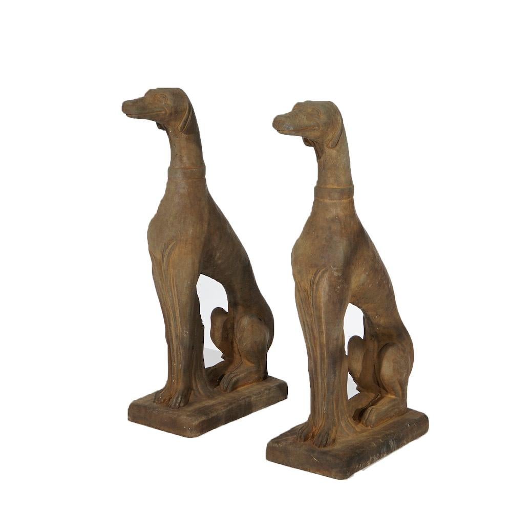 A pair of figural garden sculptures offer bronzed cast hard stone life size Whippets (dogs) in the seated position, 21st century.

Measures- 30''H x 8''W x 18''D.