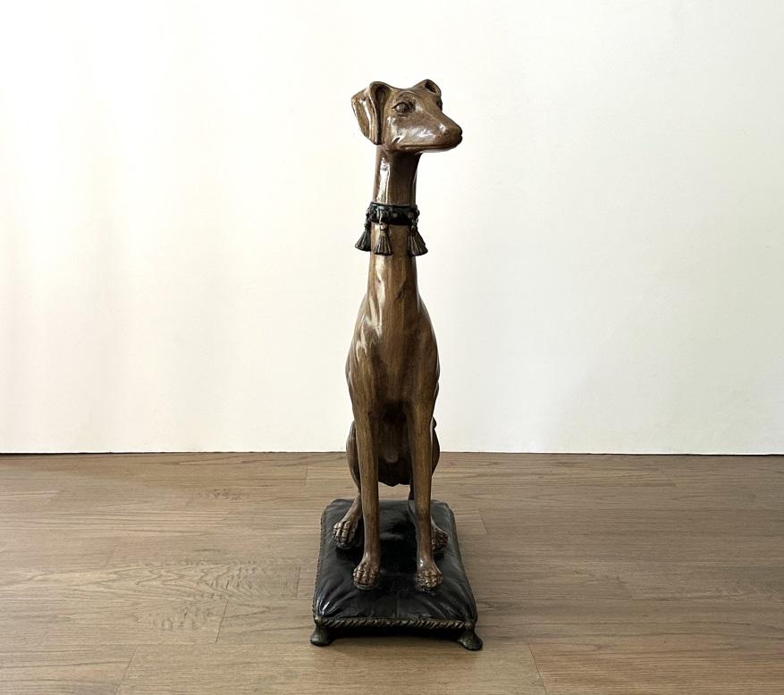Excepcional estatua de perro fustigador sentado de escayola, de gran tamaño. La majestuosidad y la elegancia de los galgos siempre han fascinado a los artistas, que los utilizan como modelos desde hace casi cinco mil años. Muestra una maravillosa