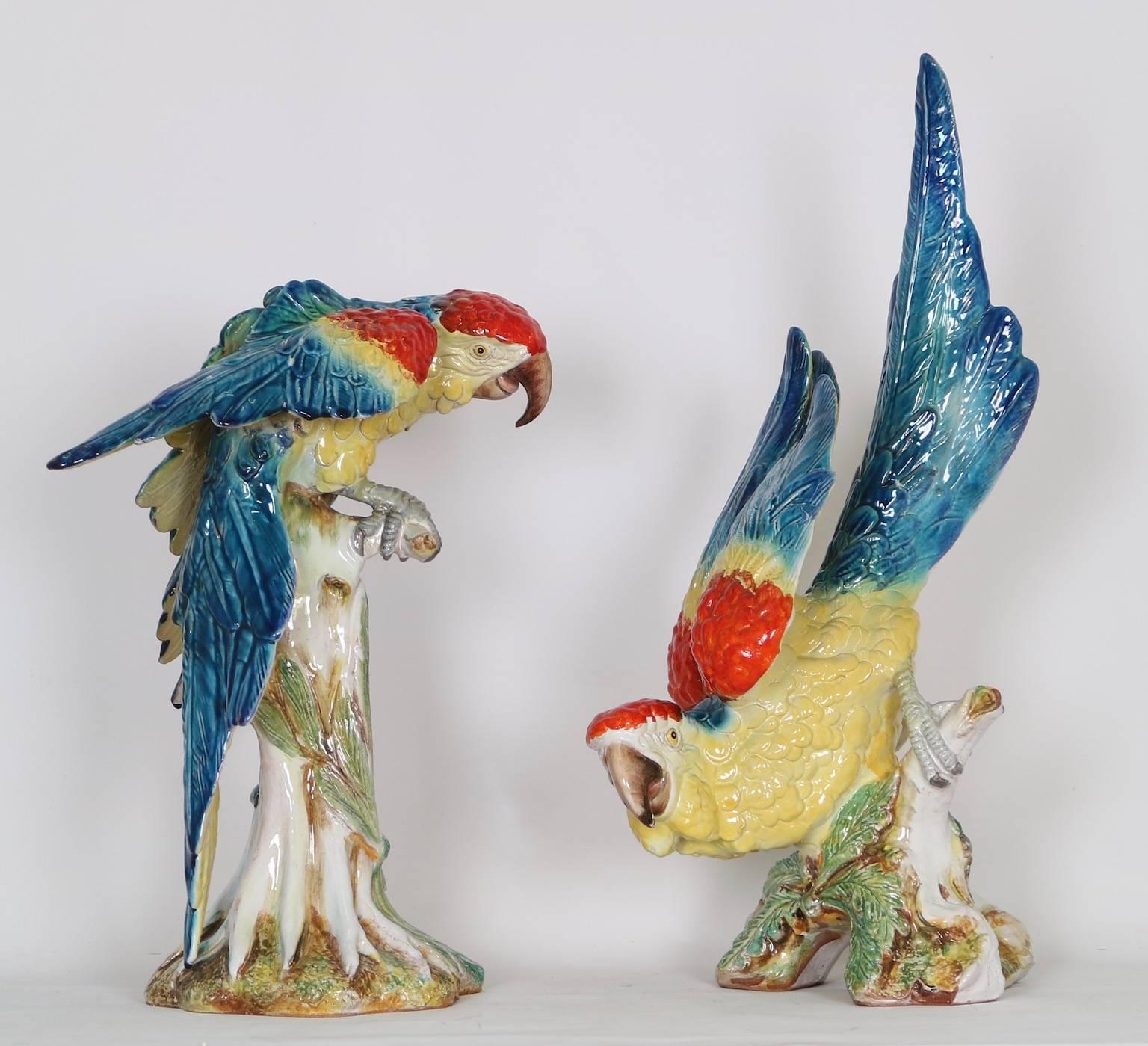 Mid-Century Modern pair of life-size macaw parrots in Italian Majolica. The parrots are painted in vivid blue, red and yellow tones. Signed by the artist- L. Landi (pictured). This pair is in excellent vintage condition and has wear consistent with