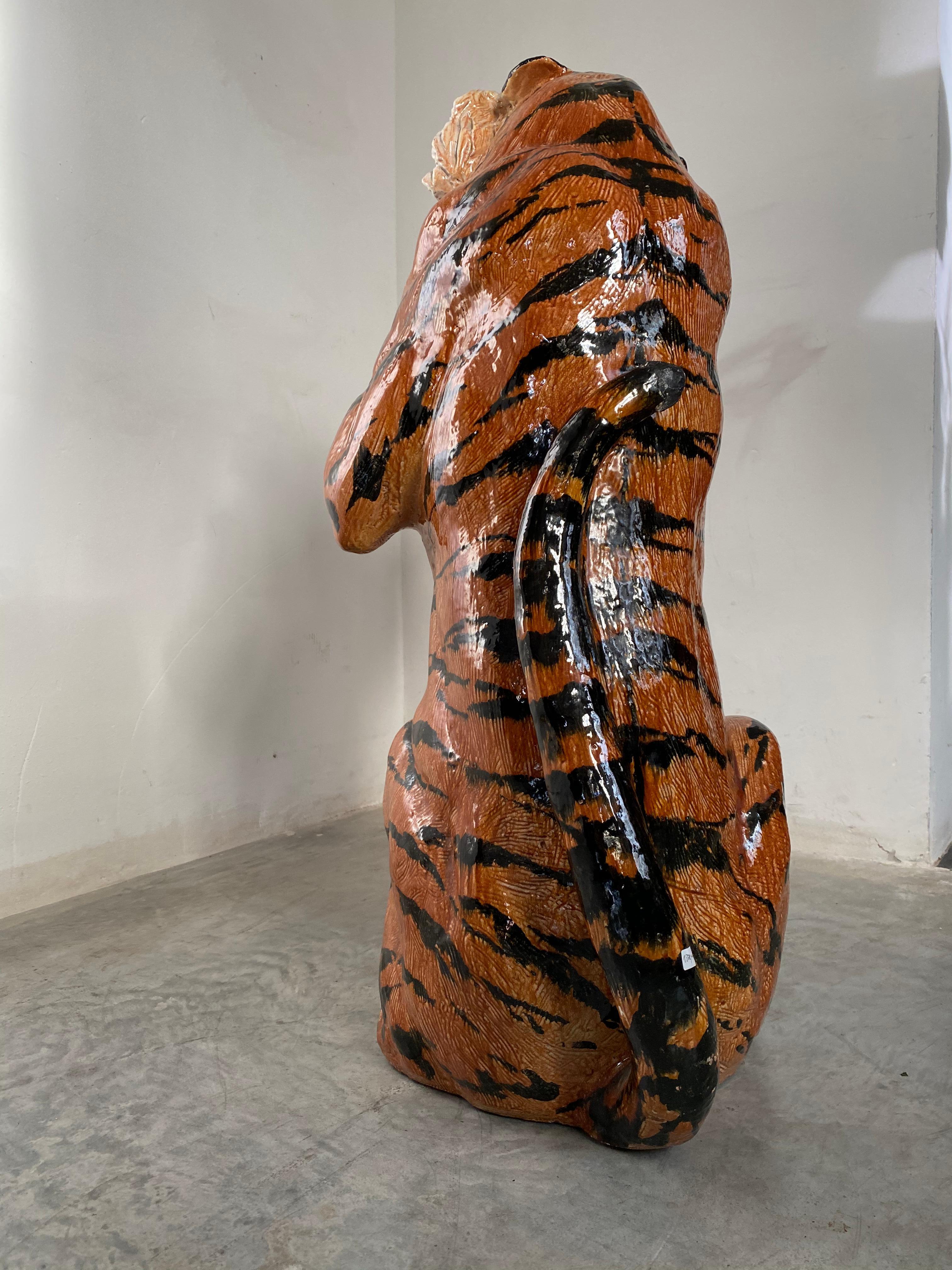 The stunning expression of a large and vibrant earthenware sculpture of a tiger, painted and glazed in white and orange-red with black markings, sitting snarling and resplendent with his teeth bared.
Made in Italy, circa 1970s. Hand executed by a