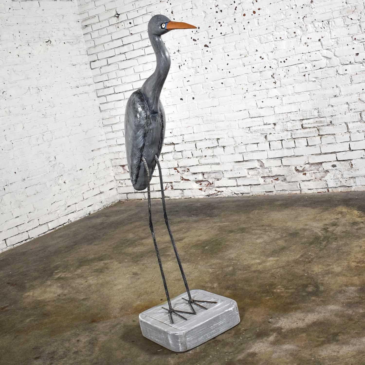 Magnificent life size blue heron carved figure on a stand. It is signed VJP 12179 and is comprised of painted wood, plaster, and rebar legs and feet. Gorgeous vintage condition with a small touch up on the neck where the plaster meets the body was