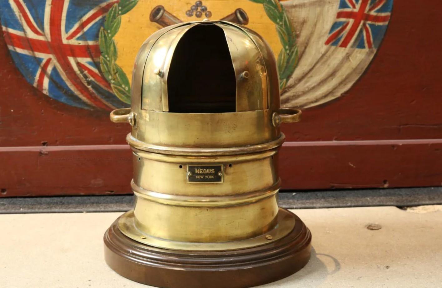 Lifeboat binnacle by Negus of New York. Brass housing, mounted to a mahogany baseboard, dry compass card reads ES Ritchie Inc. Sliding front doors. Manufacturers badge mounted to front.