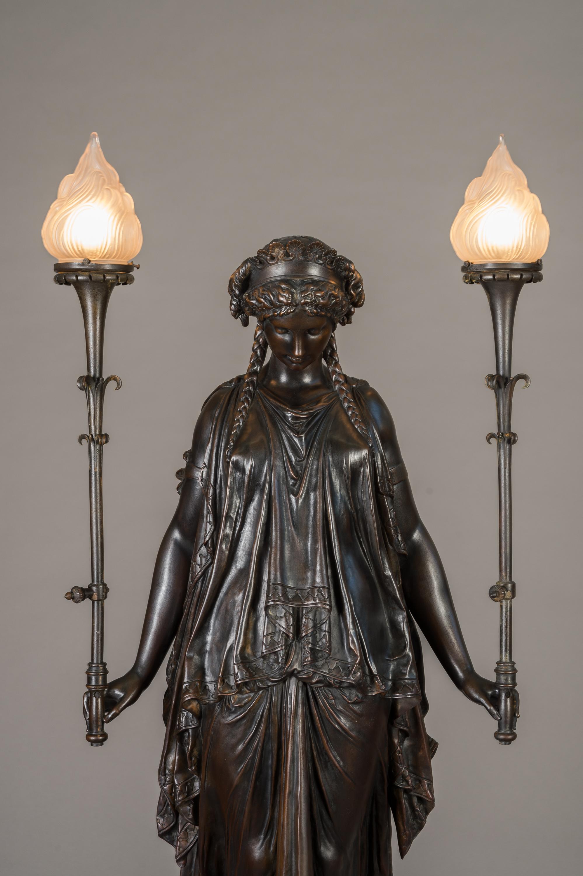 A lifesize 19th century French patinated bronze figural torchere or floorlamp

France, circa 1870

Having a wonderful dark patina depicting a fully dressed classical maiden holding two lamps. Standing on a gilt bronze ball attached to an iron