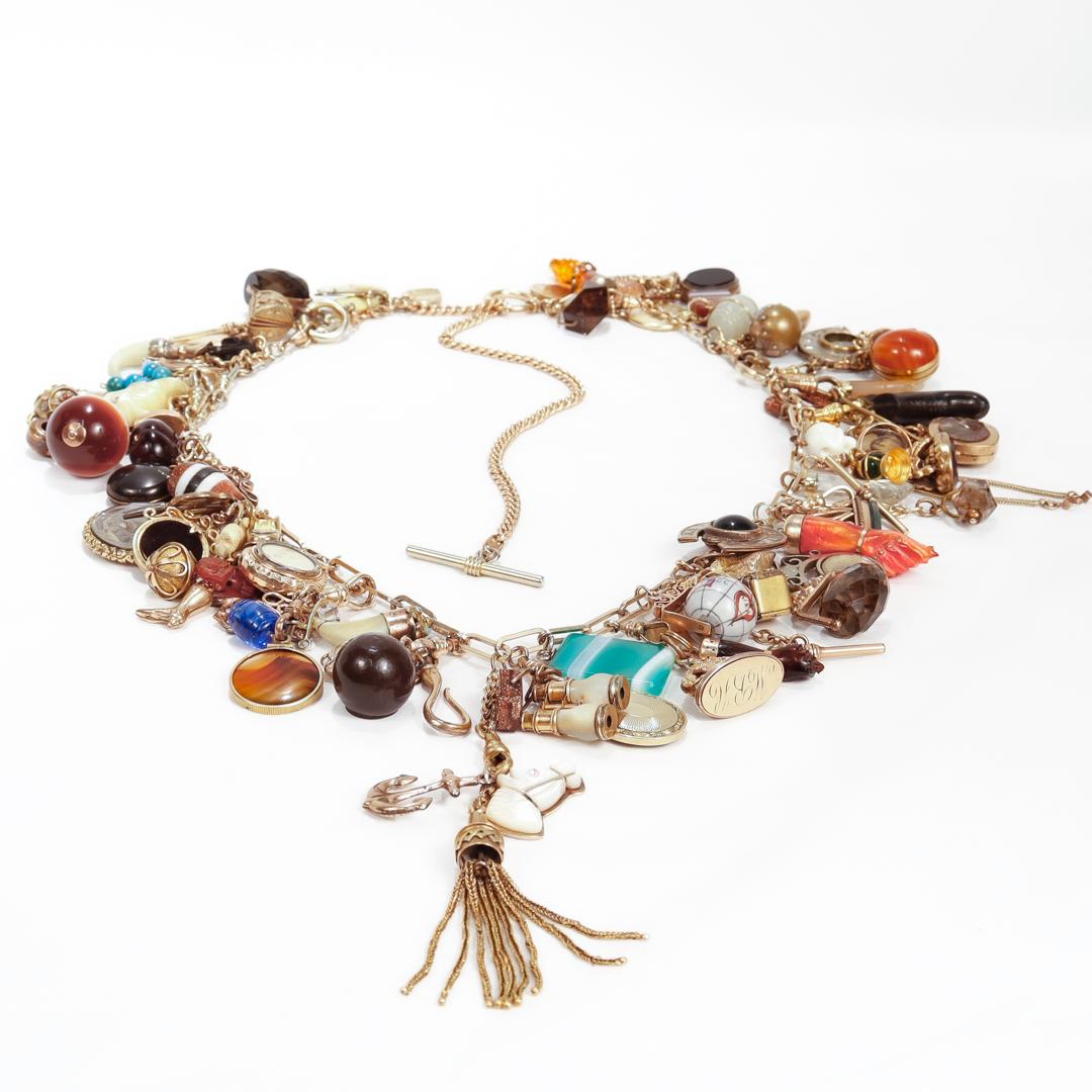 An incredible lifetime collection of antique charms fashioned as a necklace.

Comprised of over 90 charms suspended from interlinked antique gold-filled watch chains.

This necklace and its charms were assembled over decades by a long time antiques