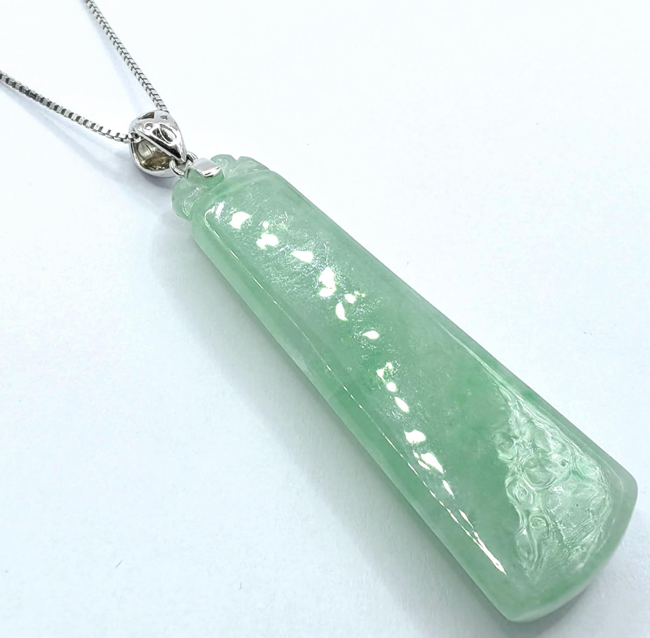 This exceptional pendant captures the essence of understated elegance through its masterful use of light apple green jadeite, expertly carved into a sleek, tapered rectangular form. The geometric minimalism showcases the jade's even translucency and