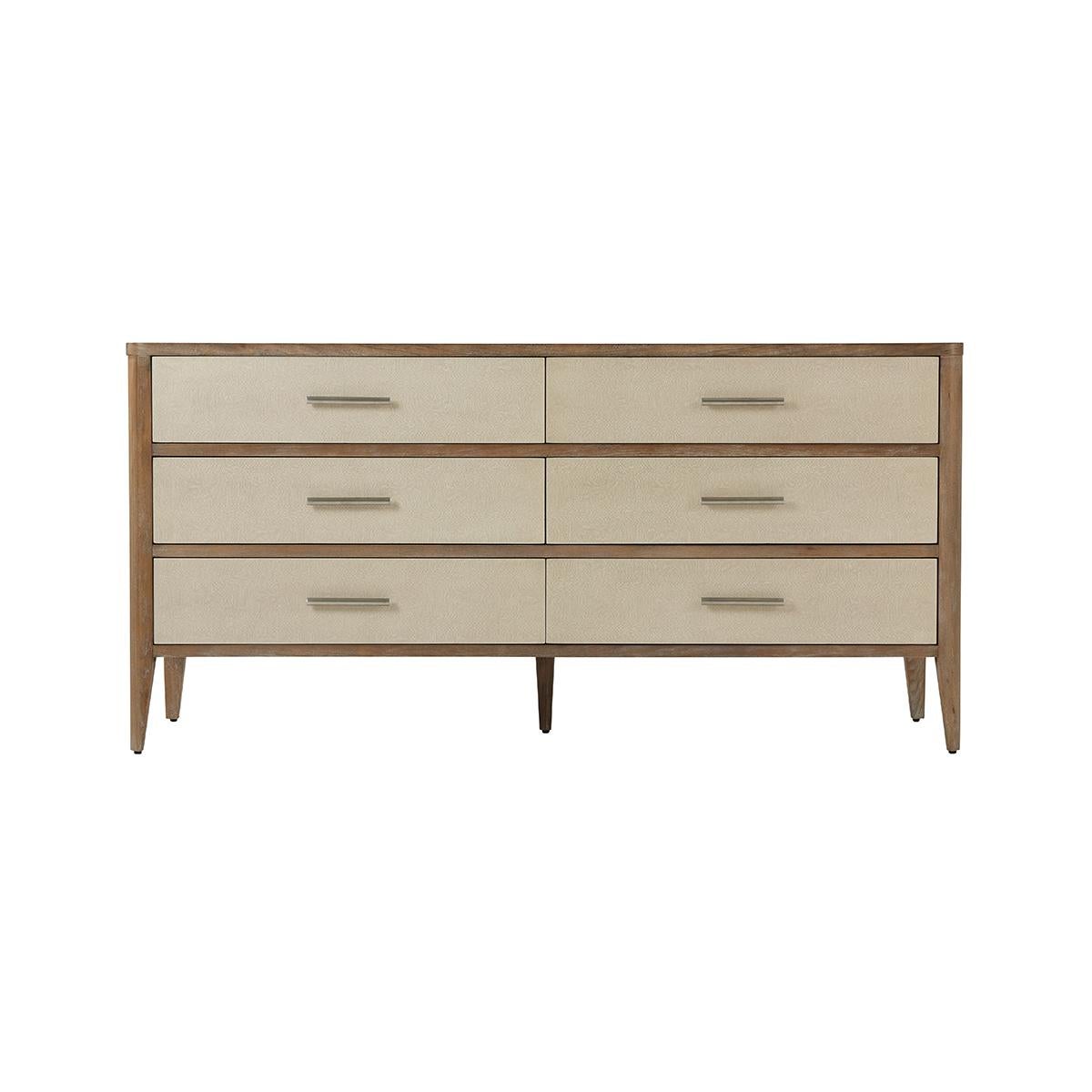 Leather Dresser in a light mangrove finish. The sides and the six drawers are wrapped in light overcast finish Komodo embossed leather. With brushed nickel finish hardware raised on flared tapering legs. 

Dimensions: 66.5