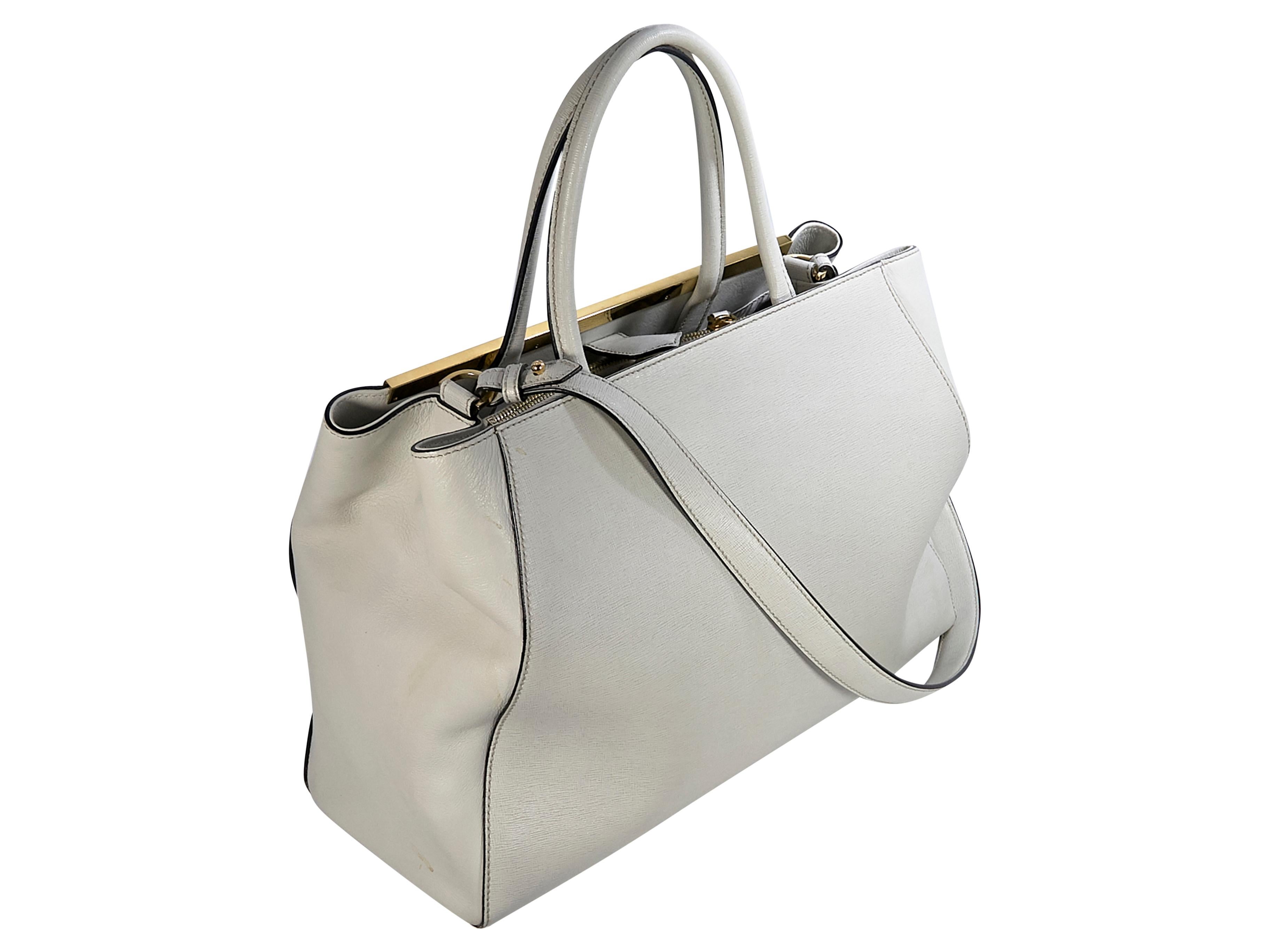 Product details:  Light beige leather 2Jours tote bag by Fendi. Dual carry handles. Detachable crossbody strap. Strap detail over top magnetic closure. Lined interior with inner zip and slide pockets. Protective metal feet. Gold-tone hardware. The