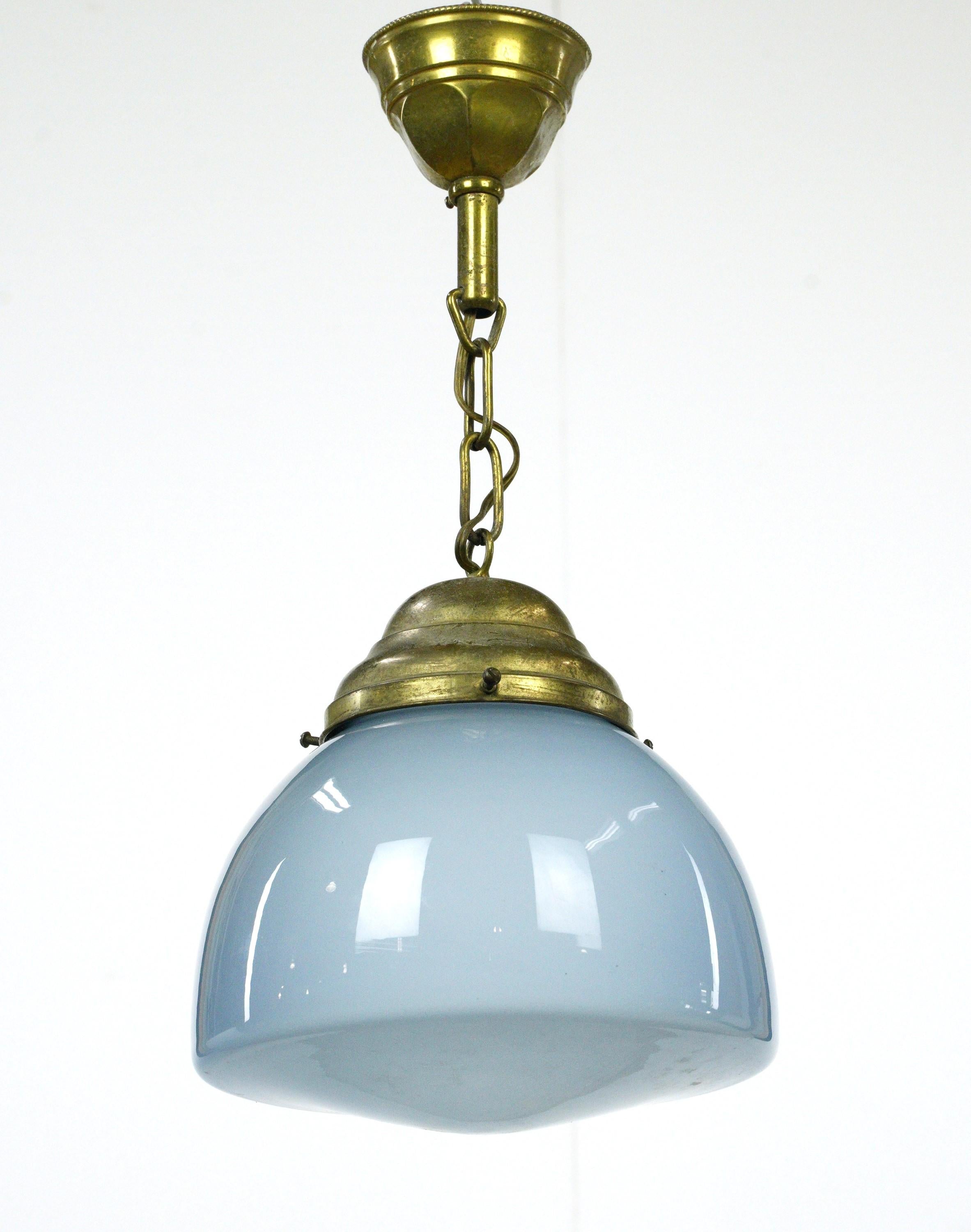 Lampe suspendue globe en verre bleu clair du 20ème siècle avec un support en laiton. Elle nécessite une ampoule standard à culot moyen. Le prix comprend la restauration, le nettoyage et le recâblage. Bon état avec une usure appropriée due à l'âge.