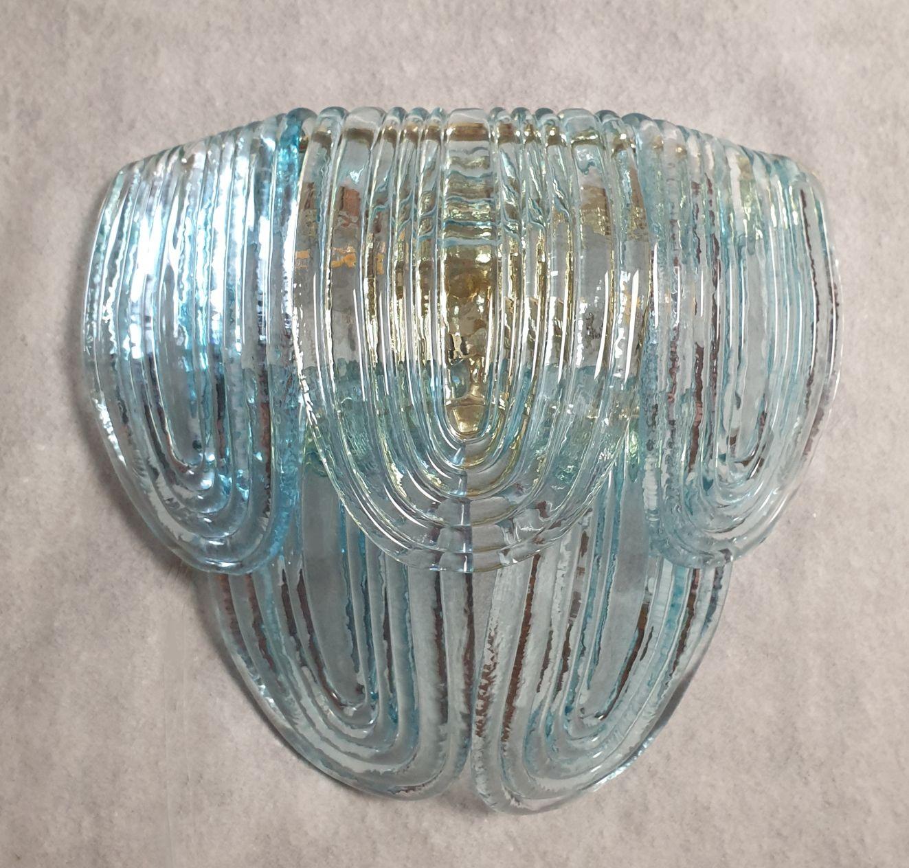 Mid-Century Modern pair of Murano glass sconces, attributed to Mazzega, Italy, 1980s.
The Italian sconces have a neoclassical style, and are very elegant.
The pair of sconces is made of translucent light blue Murano glass and a gold plated