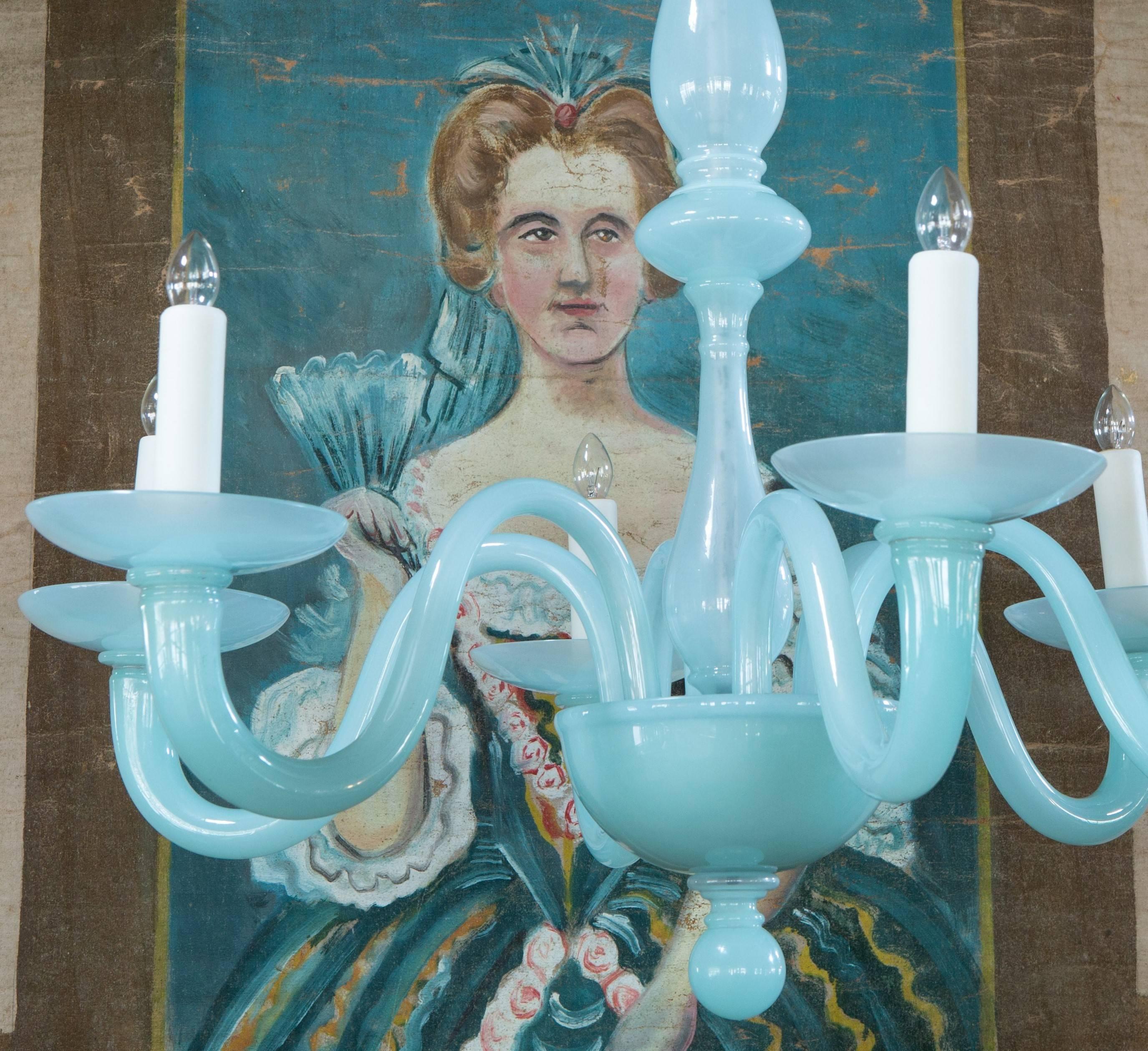 This Murano chandelier is a bit different because of its simplicity and color. We think that it could go in many rooms such as dining room,
bedroom. The color is sort of a pale turquoise milk glass or opaline. It has six arms and a bit of a