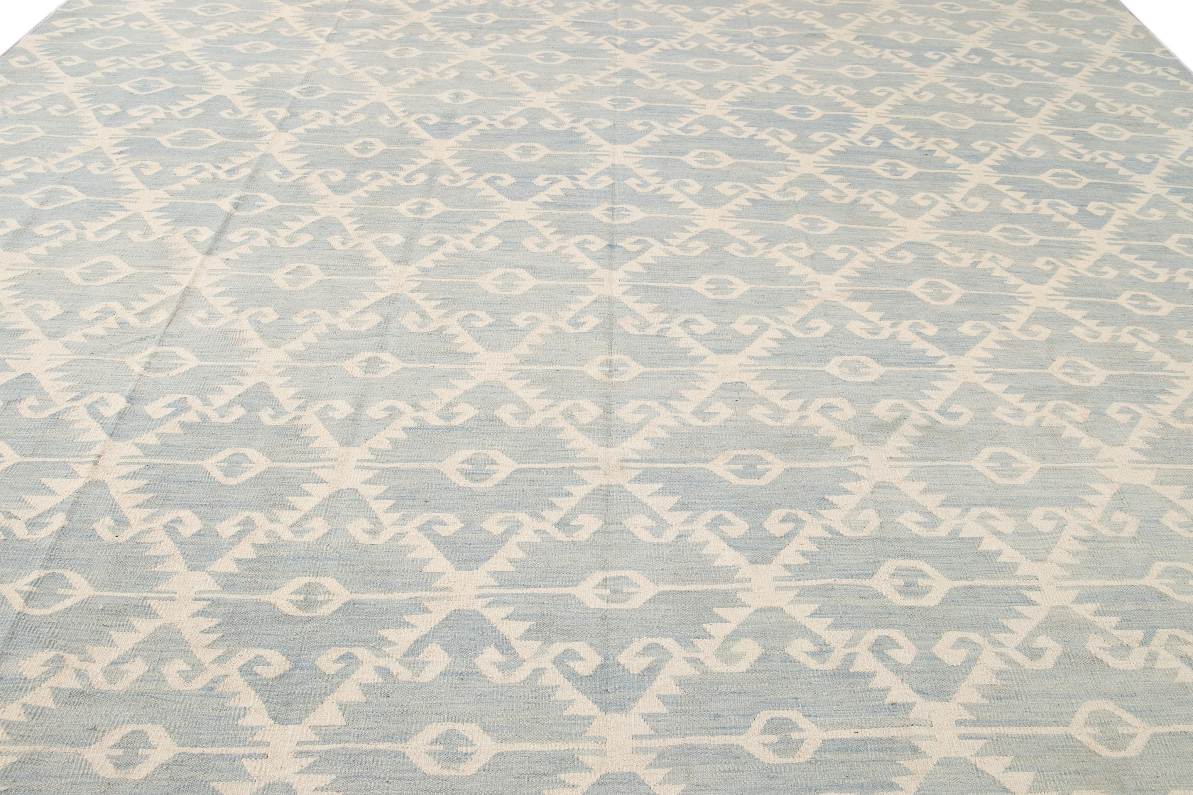 This premium wool Kilim flatweave rug displays a stunning modern beige motif. It features a light blue background with a comprehensive tribal pattern.

This rug measures 12'6