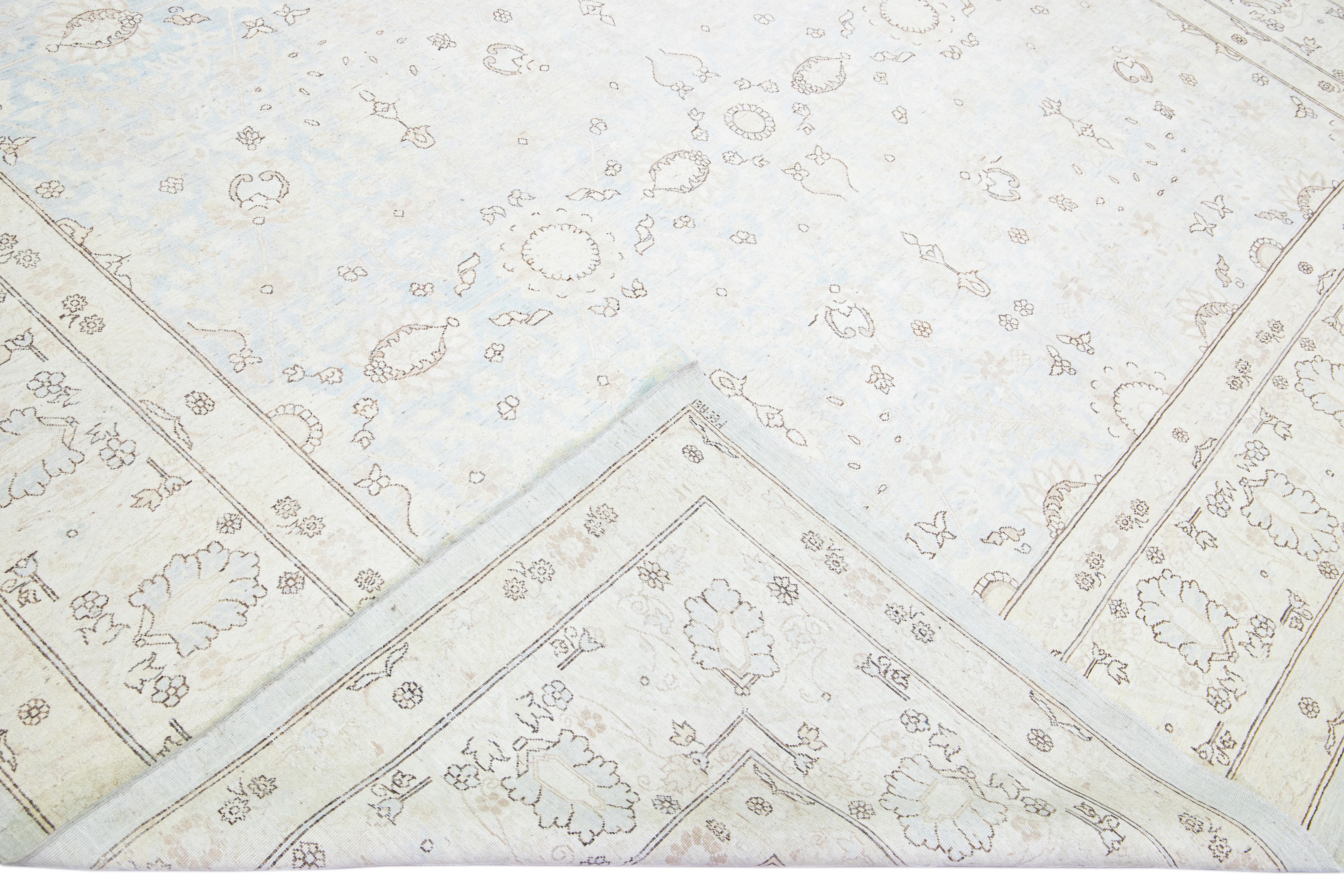 Beautiful antique Persian Tabriz style hand-knotted wool rug with a light blue field. This piece has a beige frame and brown accents in an all-over gorgeous floral design.

This rug measures 8'11