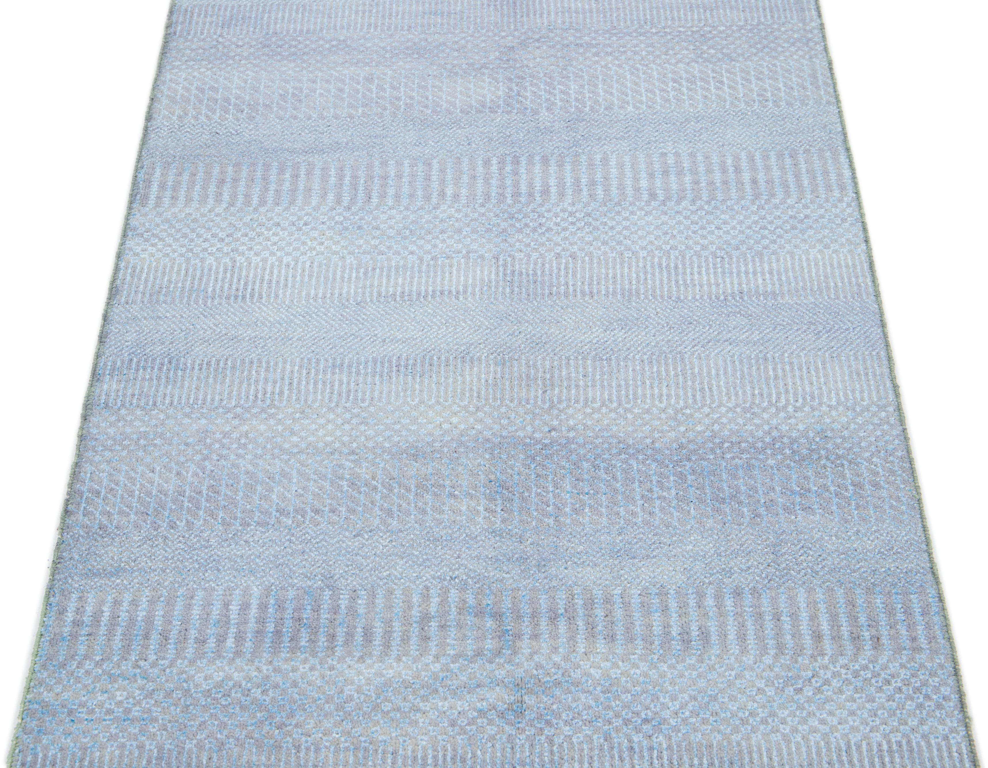 Dieser lange, handgeknüpfte Teppich ist aus Wolle gefertigt. Es zeichnet sich durch ein dezentes hellblaues Farbschema aus, das durch ein geometrisches Allover-Muster akzentuiert wird - eine ideale Ergänzung für jede moderne Einrichtung.

Dieser