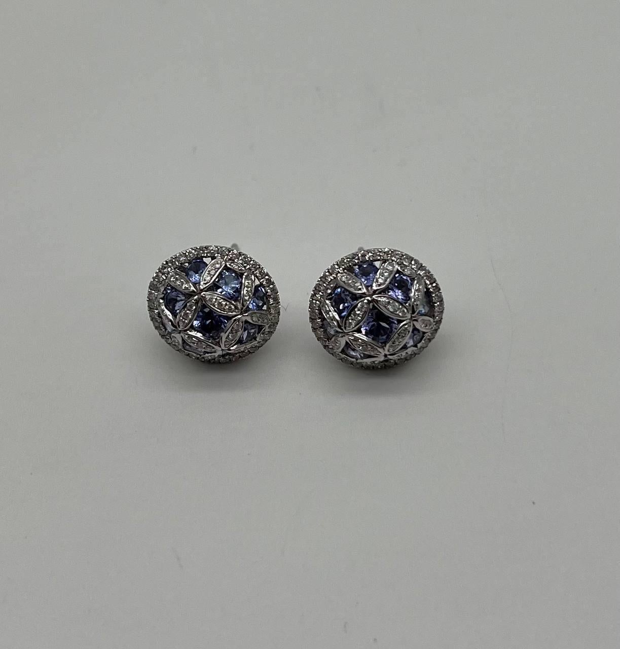 Exquisite craftsmanship of a beautiful set of earrings and ring. This stunning ring and earrings features a lattice design adorned with vibrant blue tanzanites, set in a polished 14K white gold band. Intricate detailing enhances its luxurious