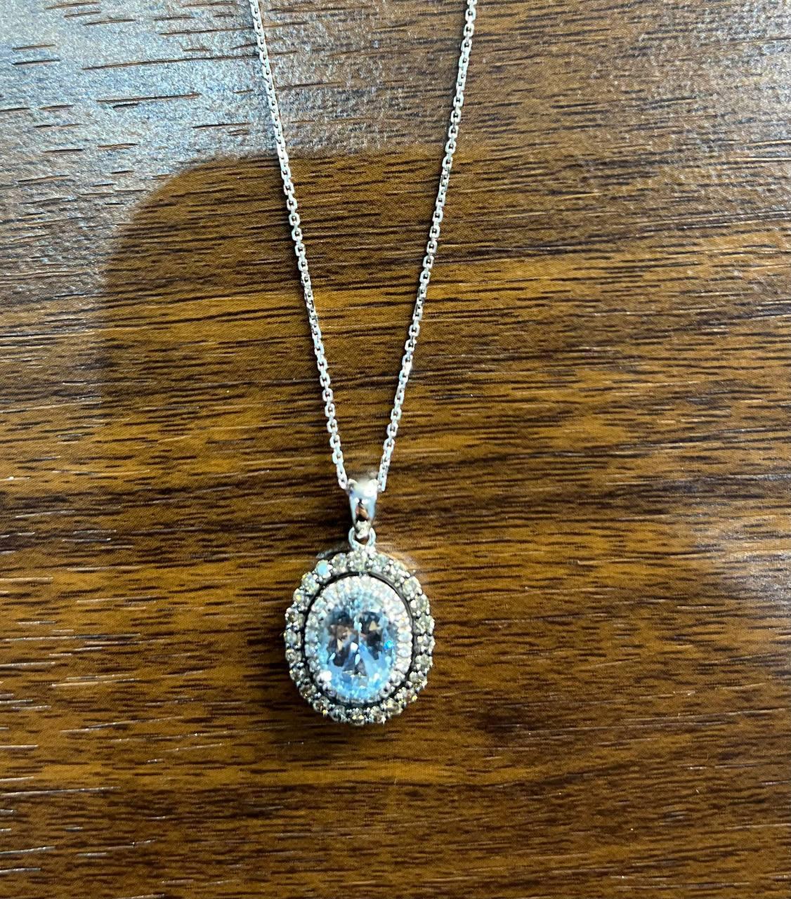 This exquisite pendant necklace is crafted with the centerpiece features a blue topaz stone, elegantly surrounded by a double halo of white diamonds.

The pendant is suspended from a delicate chain 14K White Gold.
