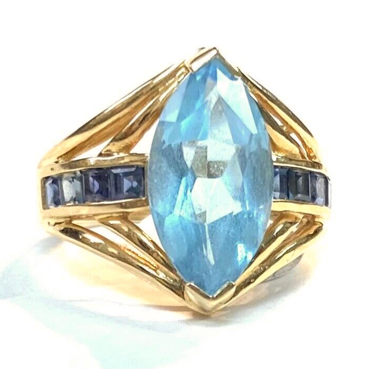 14k yellow gold marquise cut light blue topaz gemstone with dark blue topaz baguettes ,  5.28 Grams TW. The dimensions are approximately 17 mm x 8.5 mm. Approximately 5 carats. Marked14k. Approximate size 6.5.