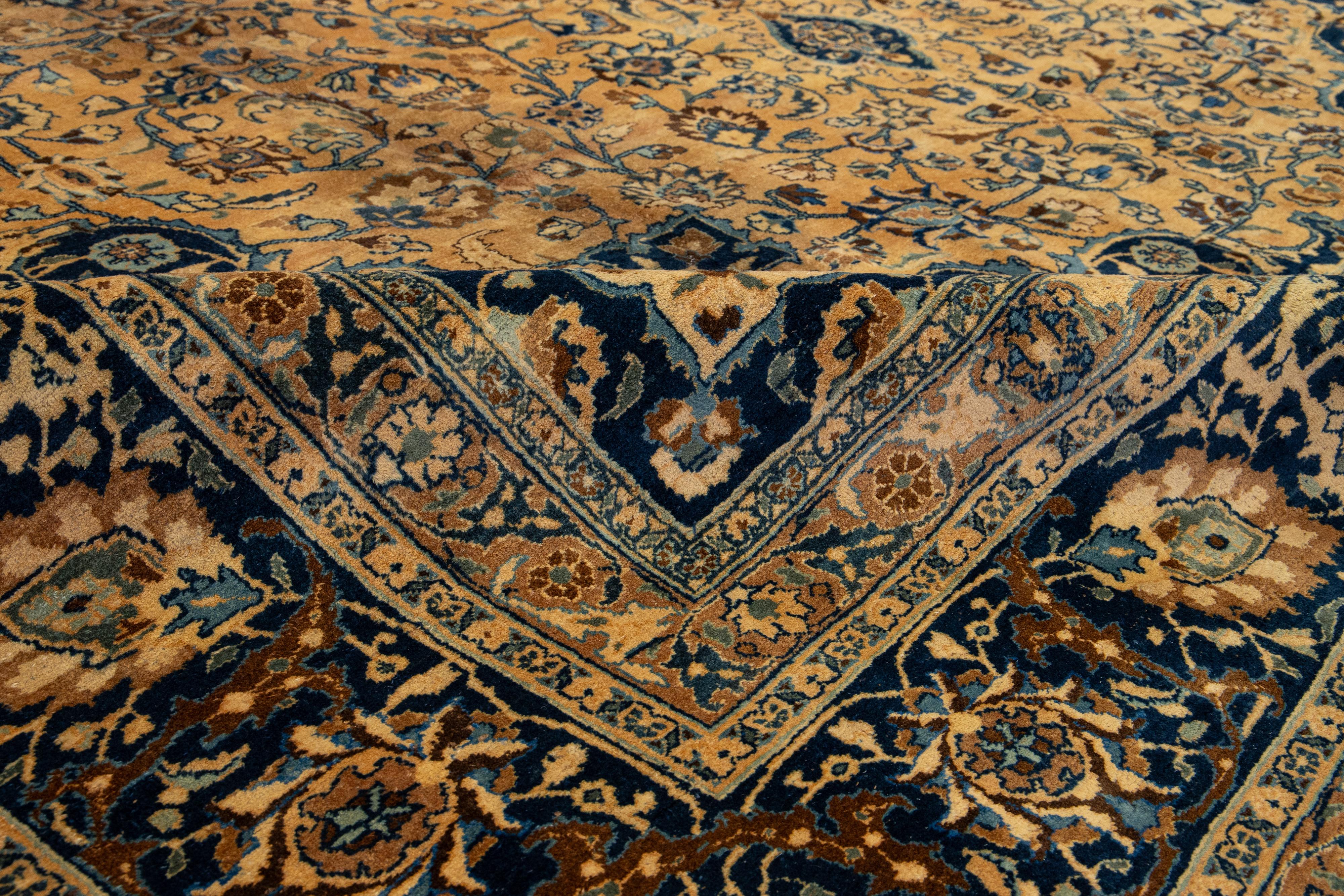 This wool rug boasts an exquisite antique Mashad hand-knotted texture. It features a deep light brown field with an intricate blue and brown classic medallion floral design.

This rug measures 11'3