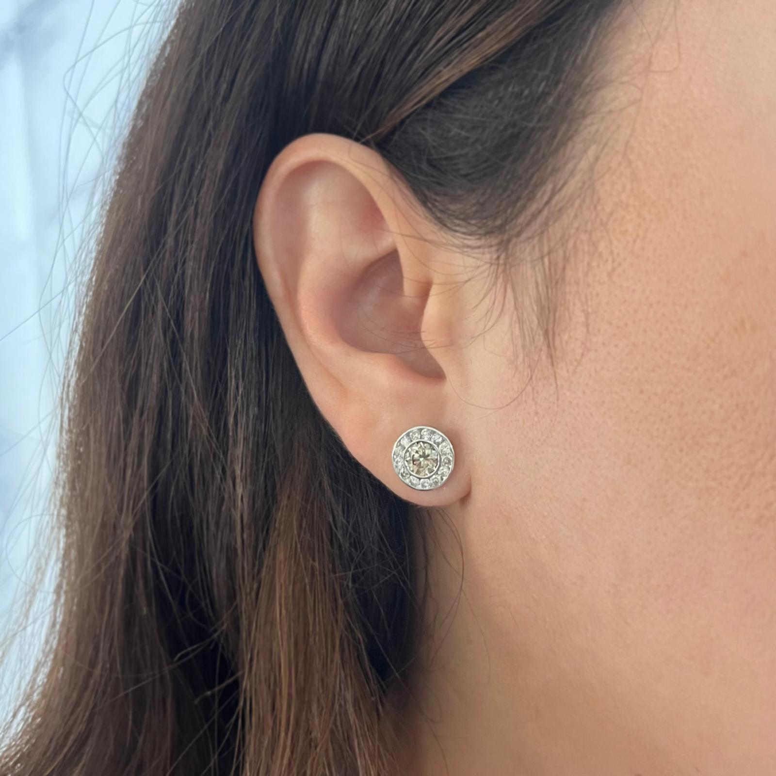 14 Karat White Gold Diamond Stud Earrings Featuring 2 Bezel Set Champagne Diamonds of VS Clarity Totaling Approximately 1.50 Carats Surrounded by 26 Channel Set Round Brilliant Cut Diamonds of SI Clarity and H Color Totaling 0.52 Carats. Pierced