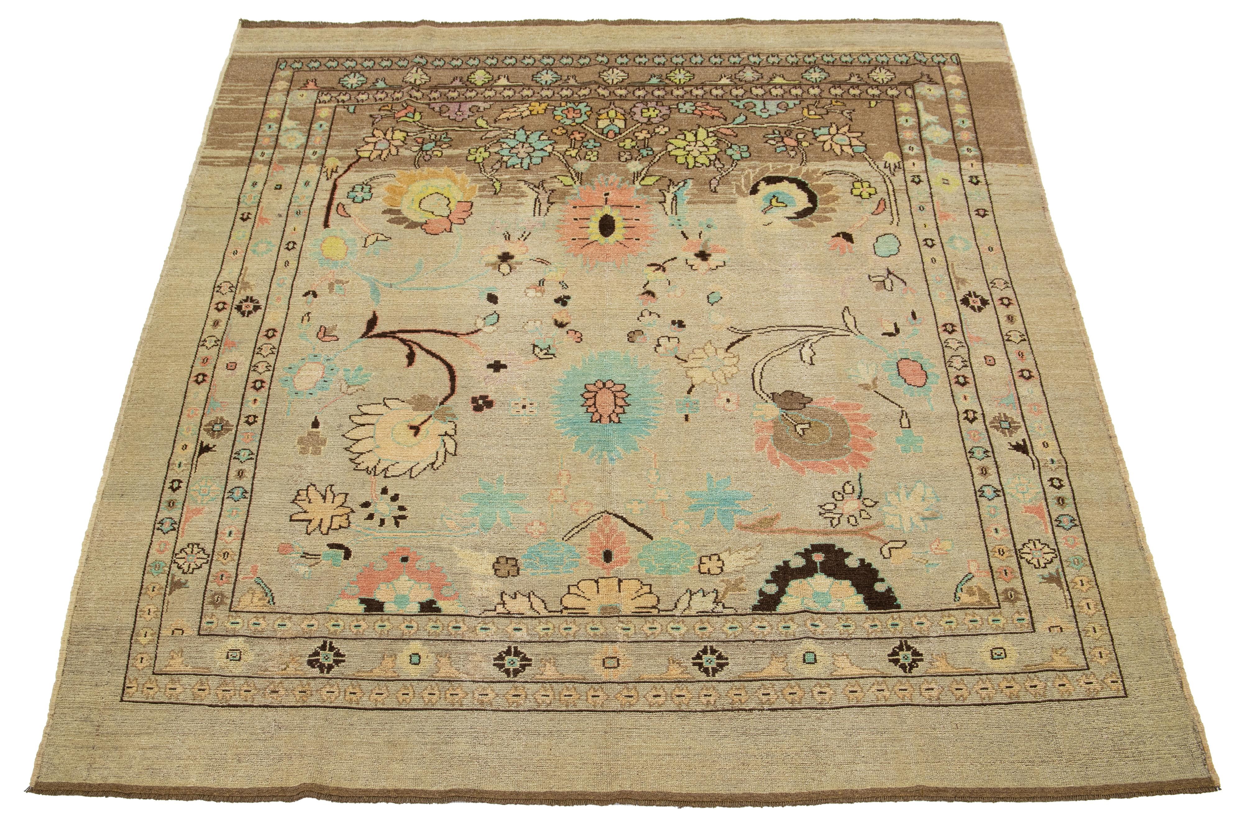 Beautiful modern hand-knotted wool rug with a light brown base. This rug from the Apadana Revival Collection features an eye-catching geometric and botanical floral design with accents in teal, peach, brown, and yellow.

This rug measures 8' x
