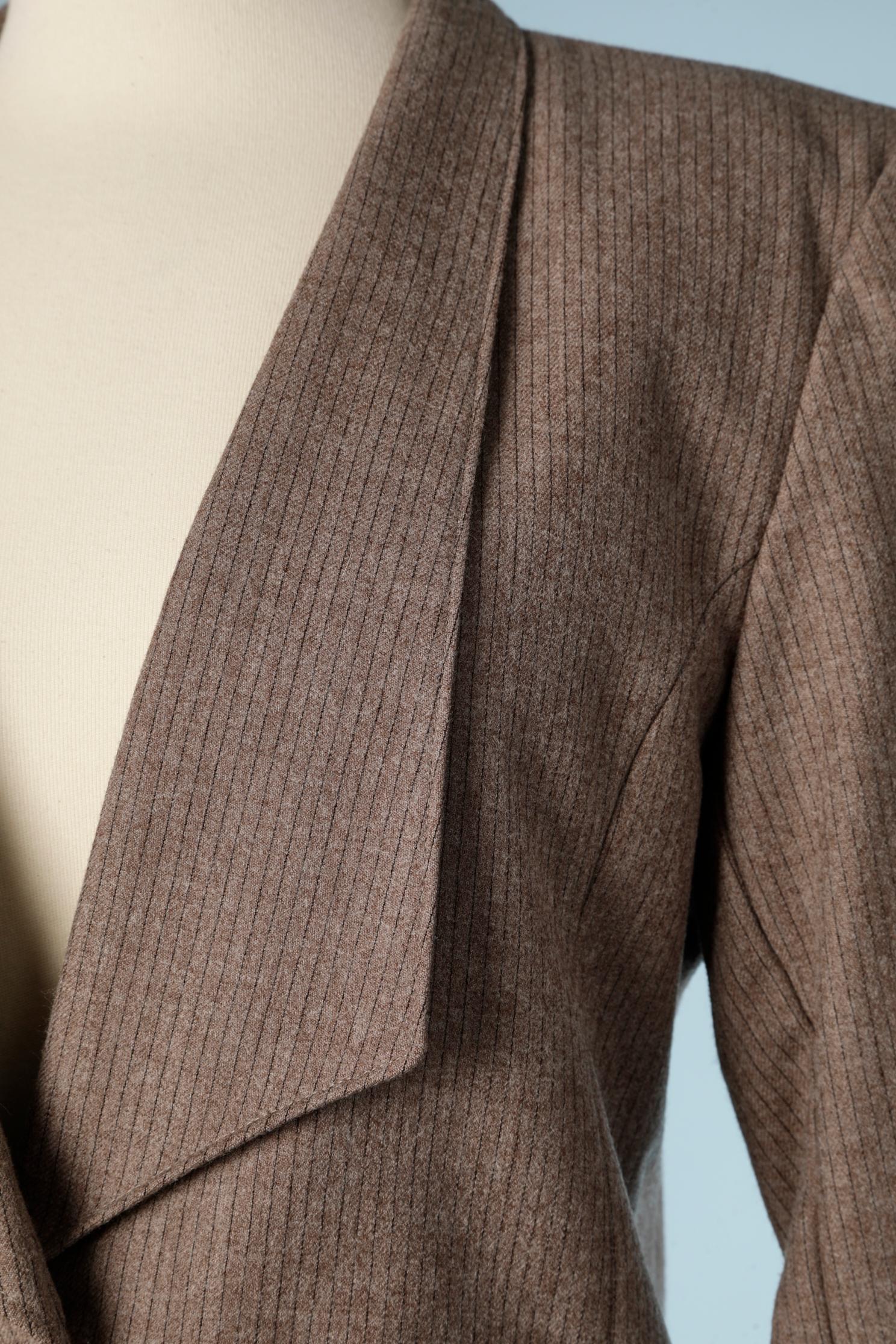 Tailleur jupe en laine marron clair à fines rayures. La jupe est enveloppée et comporte un bouton à l'avant avec quelques plis.
TAILLE S