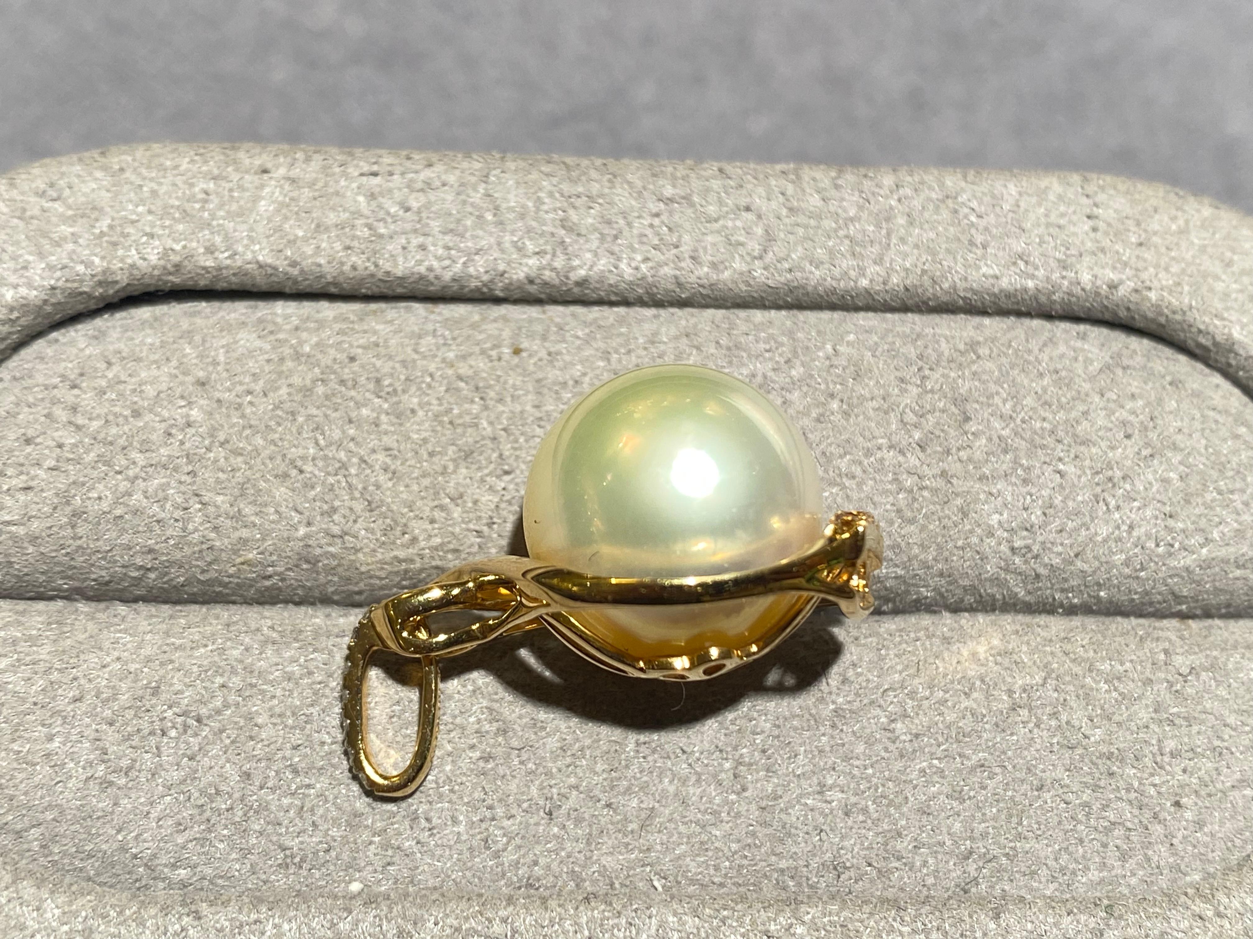 A round 12.5 mm light champagne colour south sea pearl and diamond pendant in 18k yellow gold. The pendant resemble that of a vase with flat bottom and wide stomach. At the bottom of the pendant are yellow diamond pave and white diamonds are set on