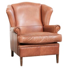 Light cognac-coloured cow leather wingback armchair with matching piping