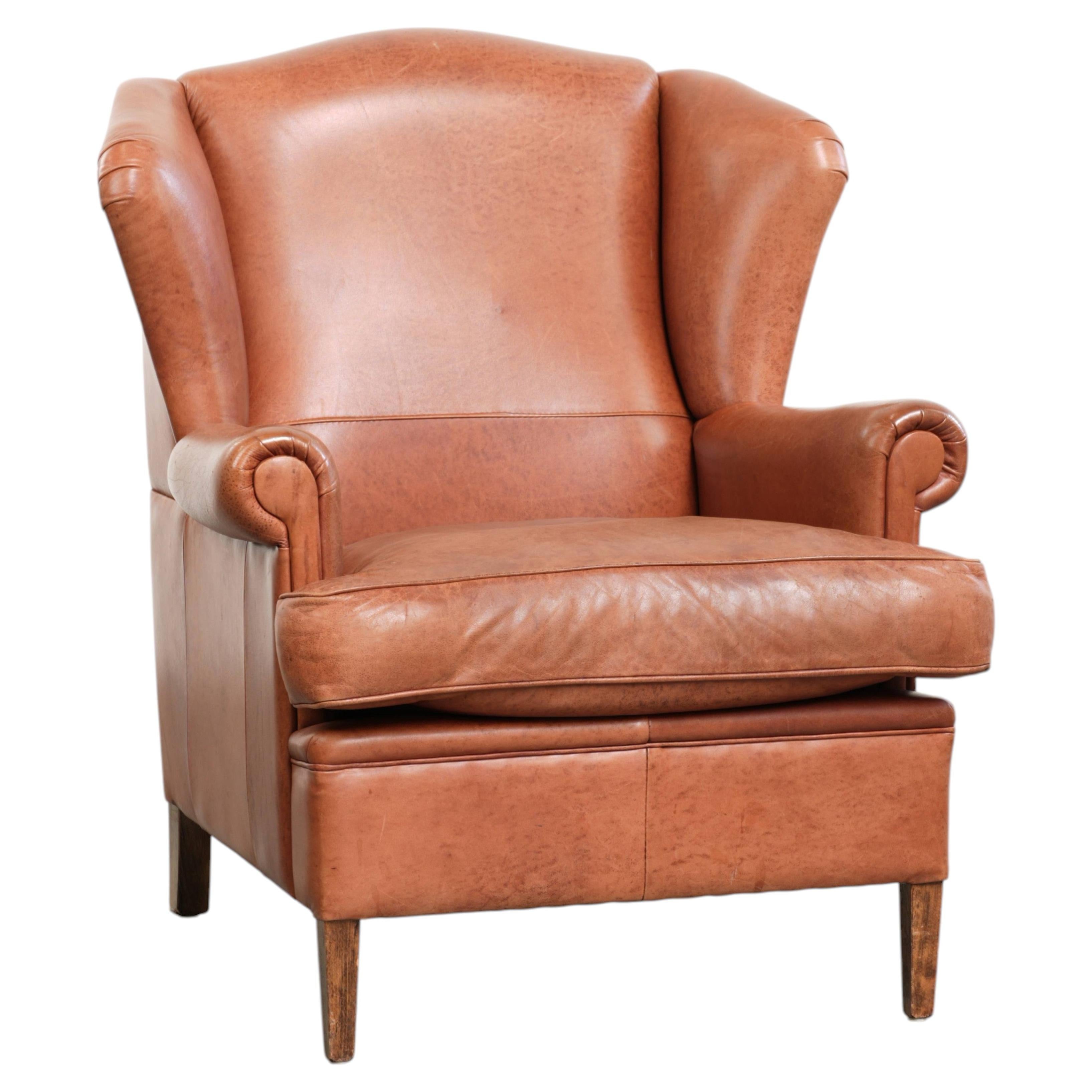 Light cognac-coloured English wingback armchair made of cowhide leather