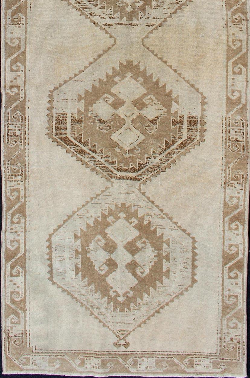 Medallion Oushak gallery carpet, Keivan Woven Arts / rug tu-alk-4862, country of origin / type: Turkey / Oushak, circa 1940. Light colored vintage Oushak runner with geometric medallions

This Oushak carpet from mid-20th century Turkey features a